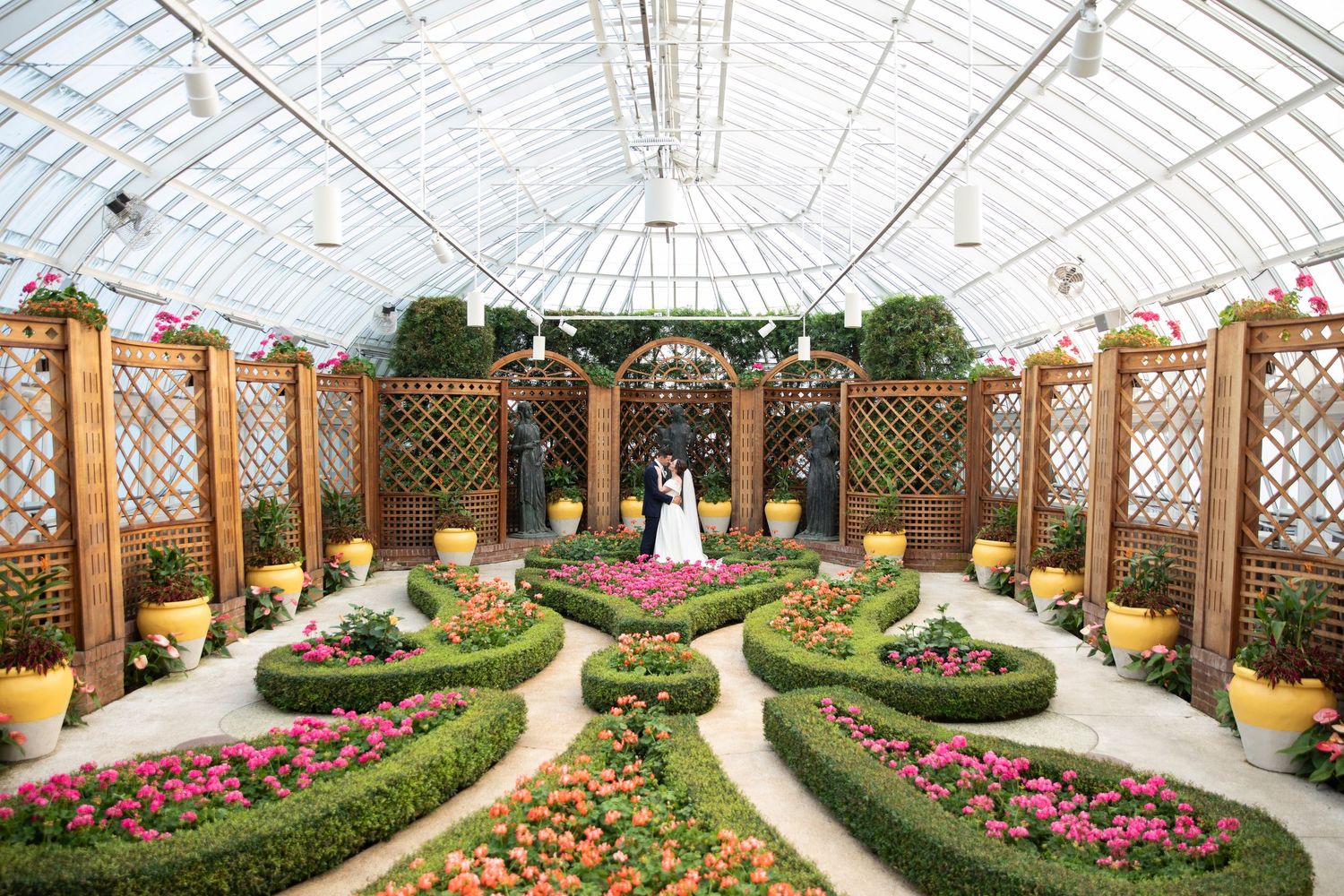 Greenhouse wedding venue with curved pathways lined with colorful flower gardens.