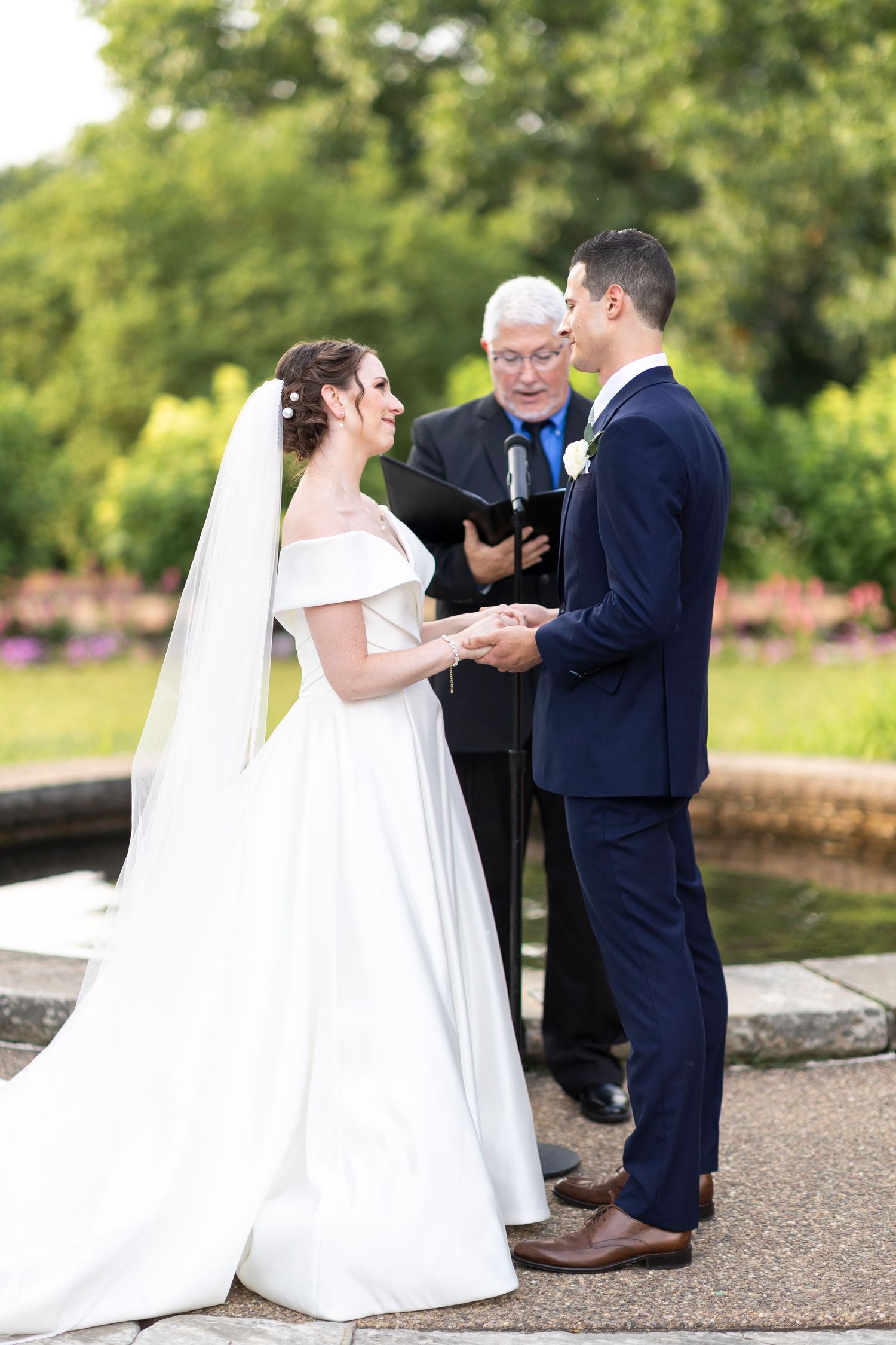 Wedding ceremony taking place outdoors with couple exchanging vows in front of officiant.