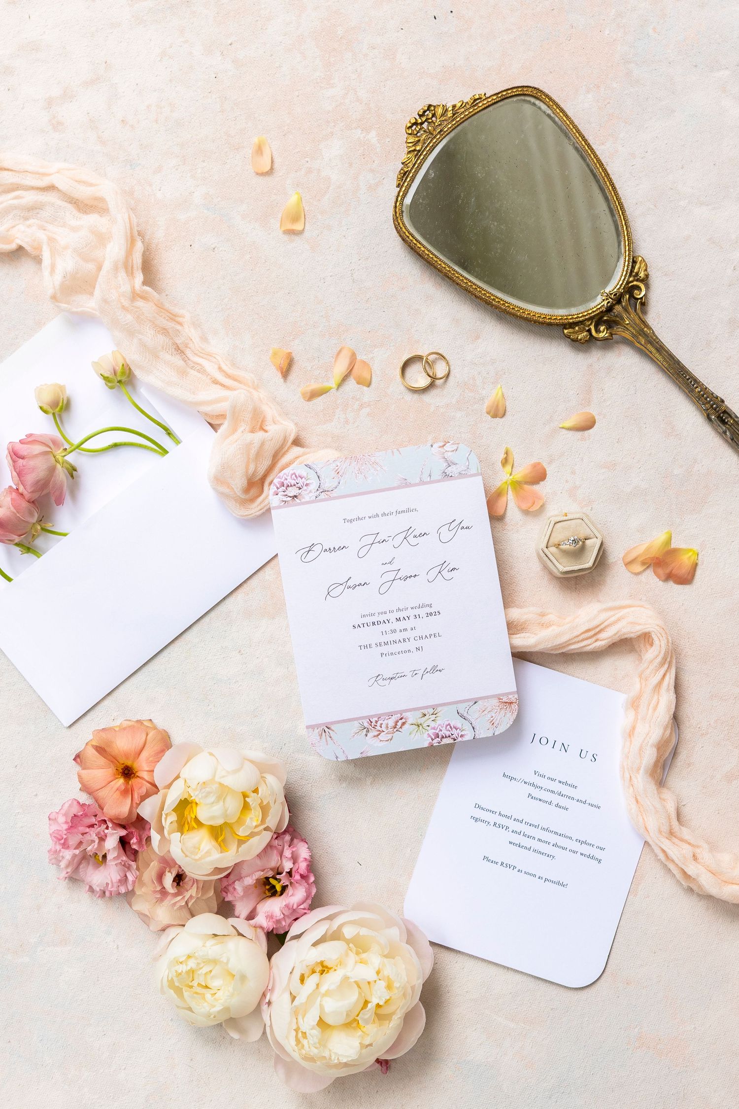 Elegant wedding invitation suite with pink florals and vintage hand mirror on light background.