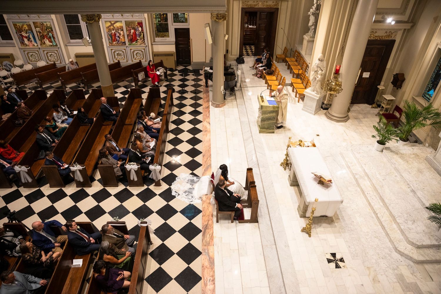 Wedding ceremony in a grand church with black and white checkered floor.