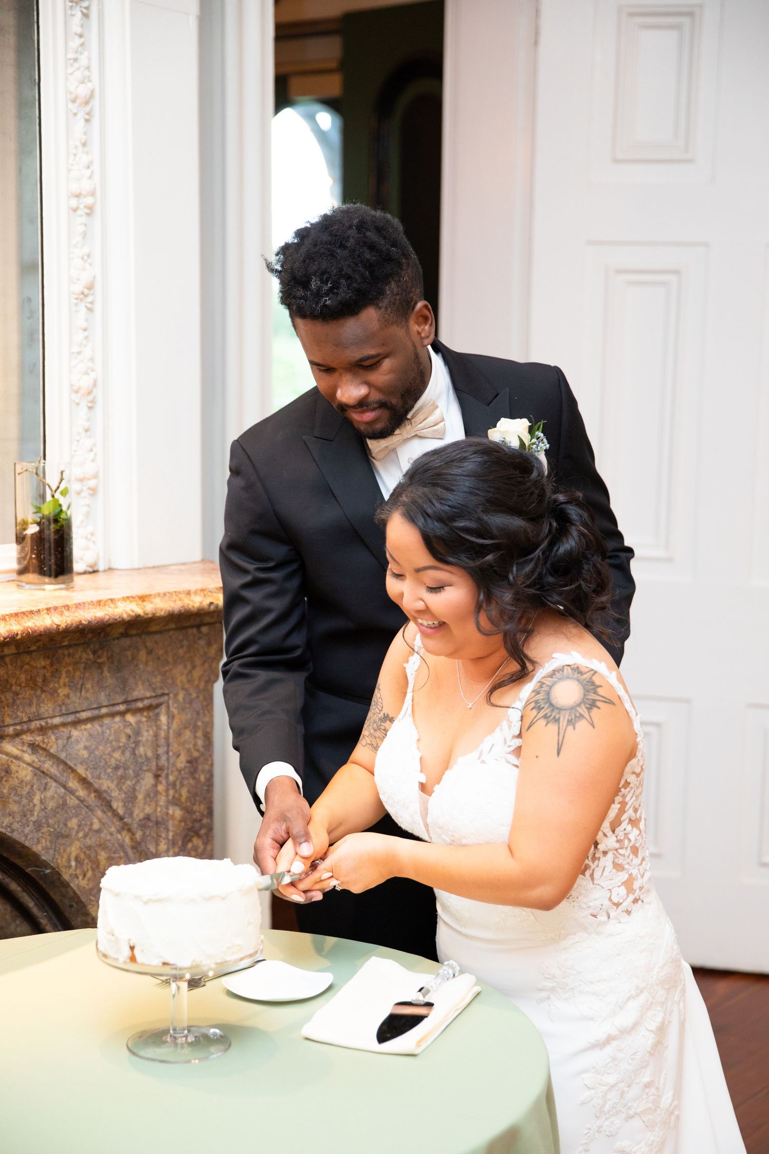 Newlyweds share cake at a small table during their wedding reception.
