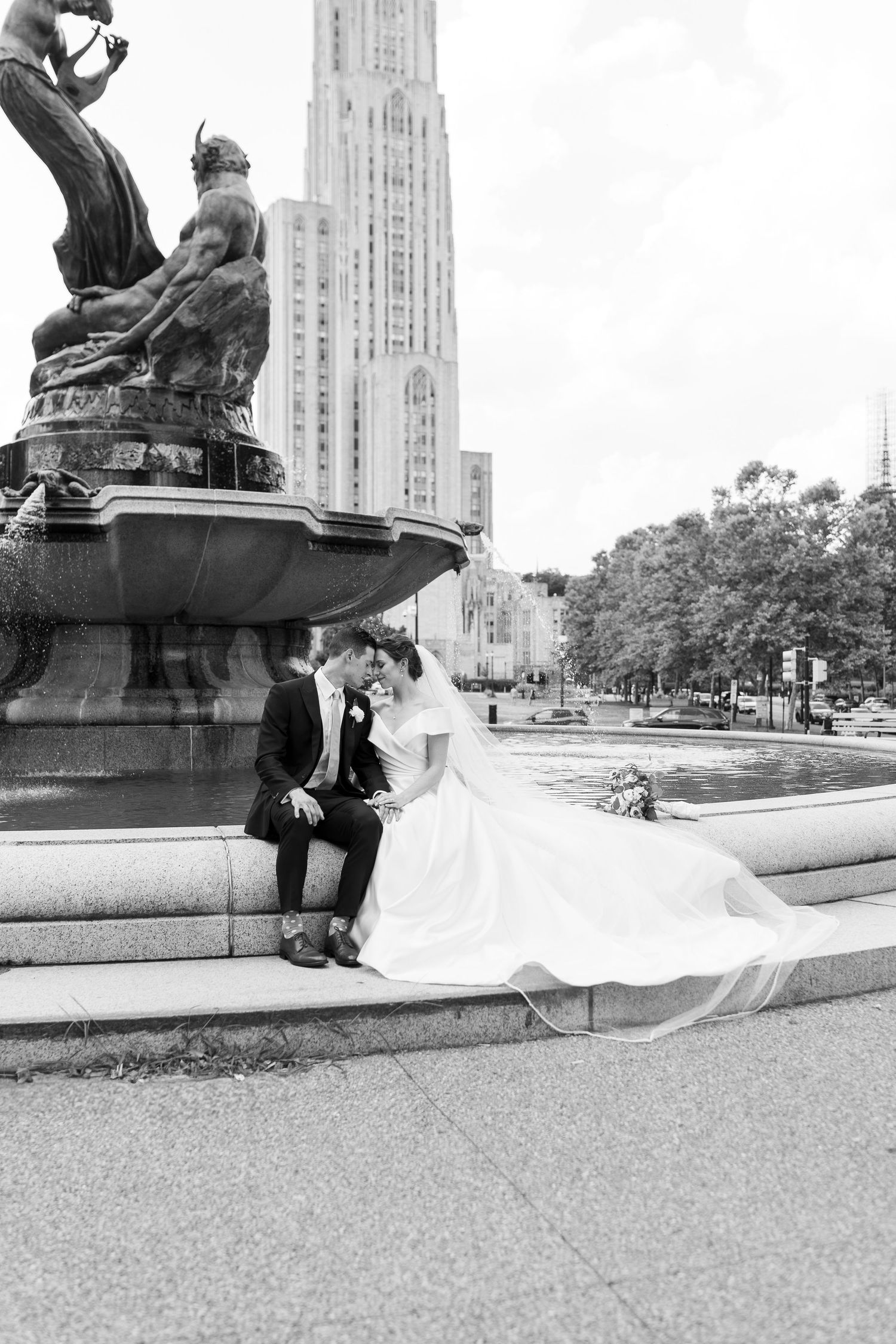 Black and white photo of a couple sitting near a cathedral building with dramatic architecture.