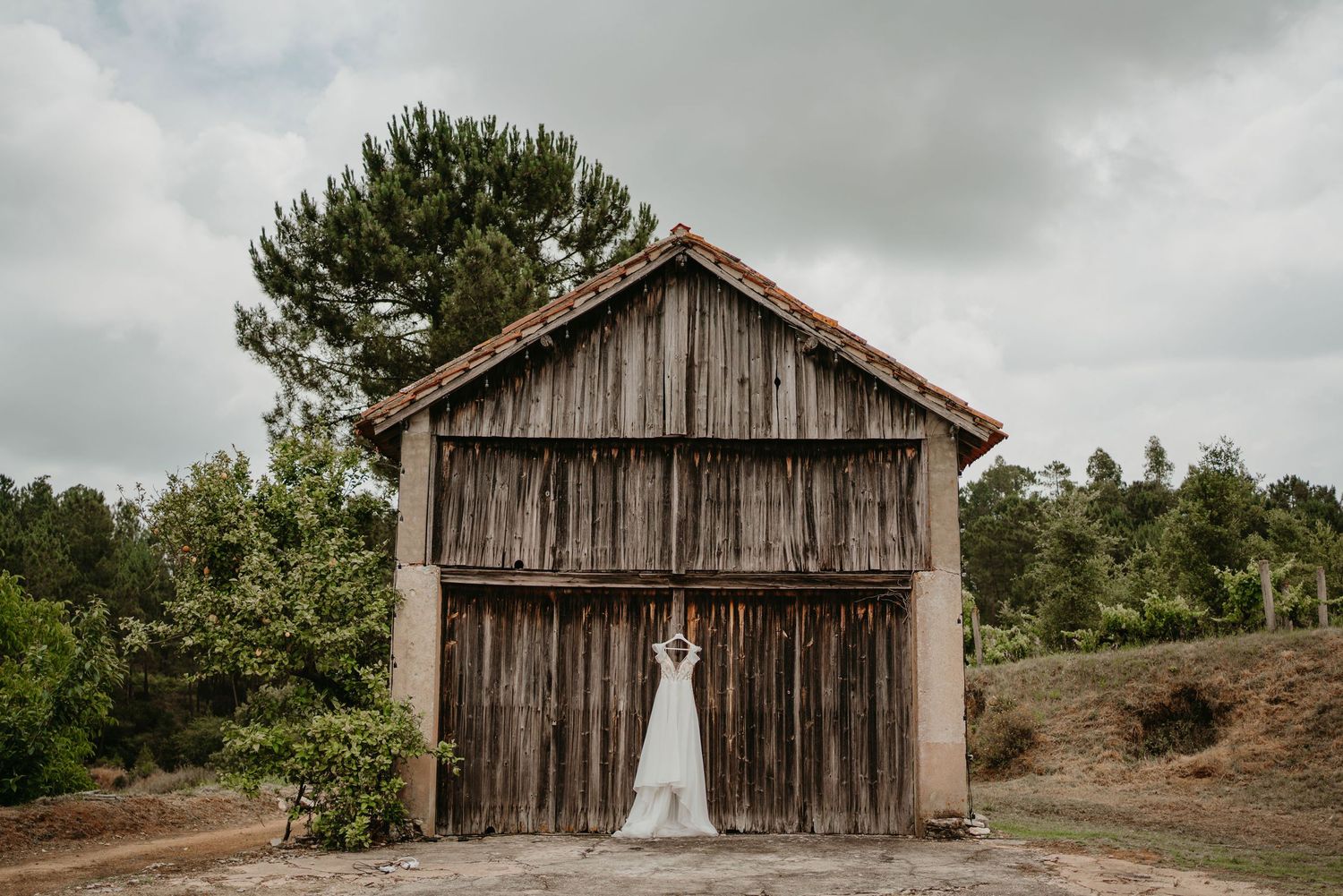Bride wedding dress in front of a rustic wooden barn at Colina dos Piscos, Portugal