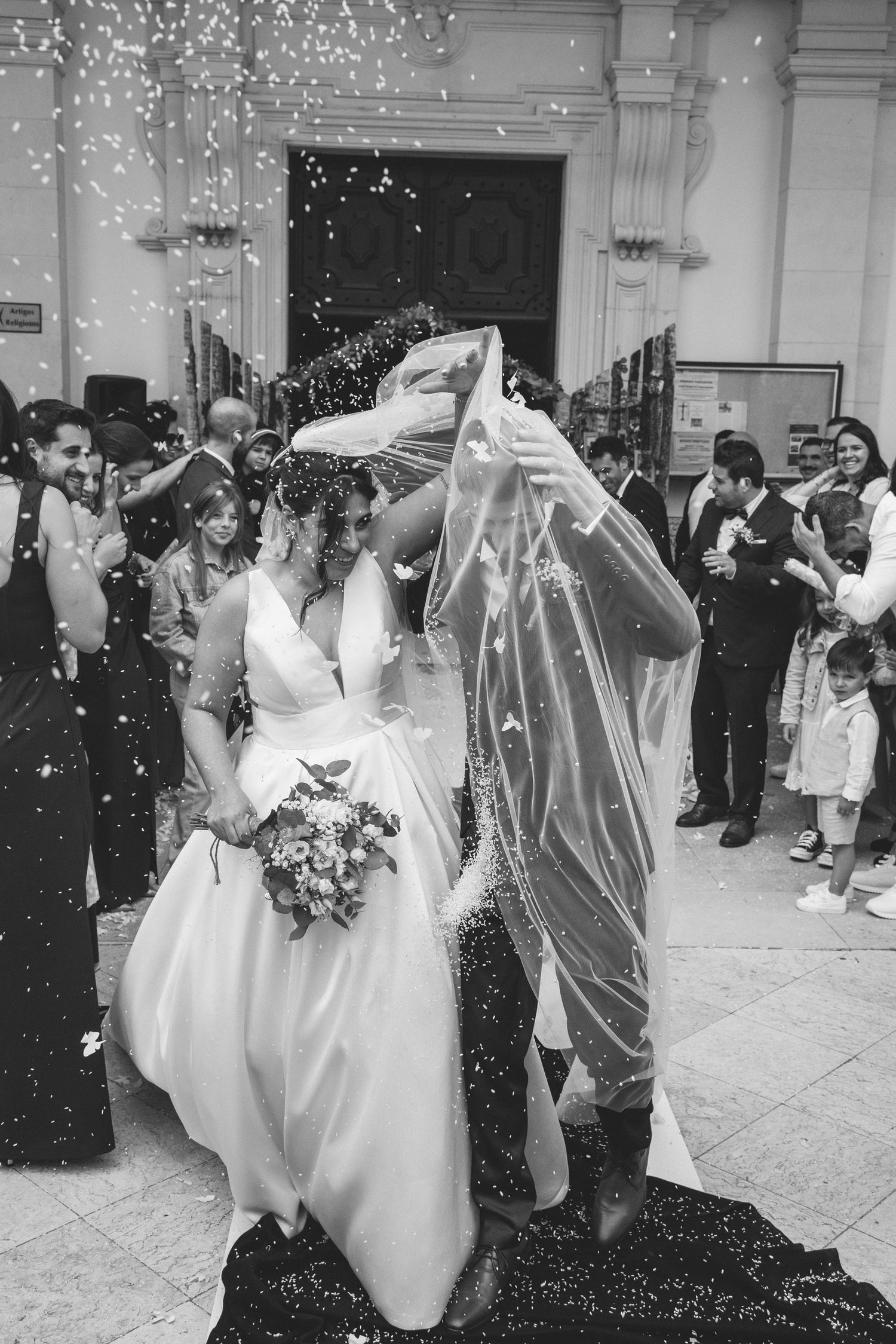 Bride and groom leaving their wedding ceremony surrounded by guests in Portugal