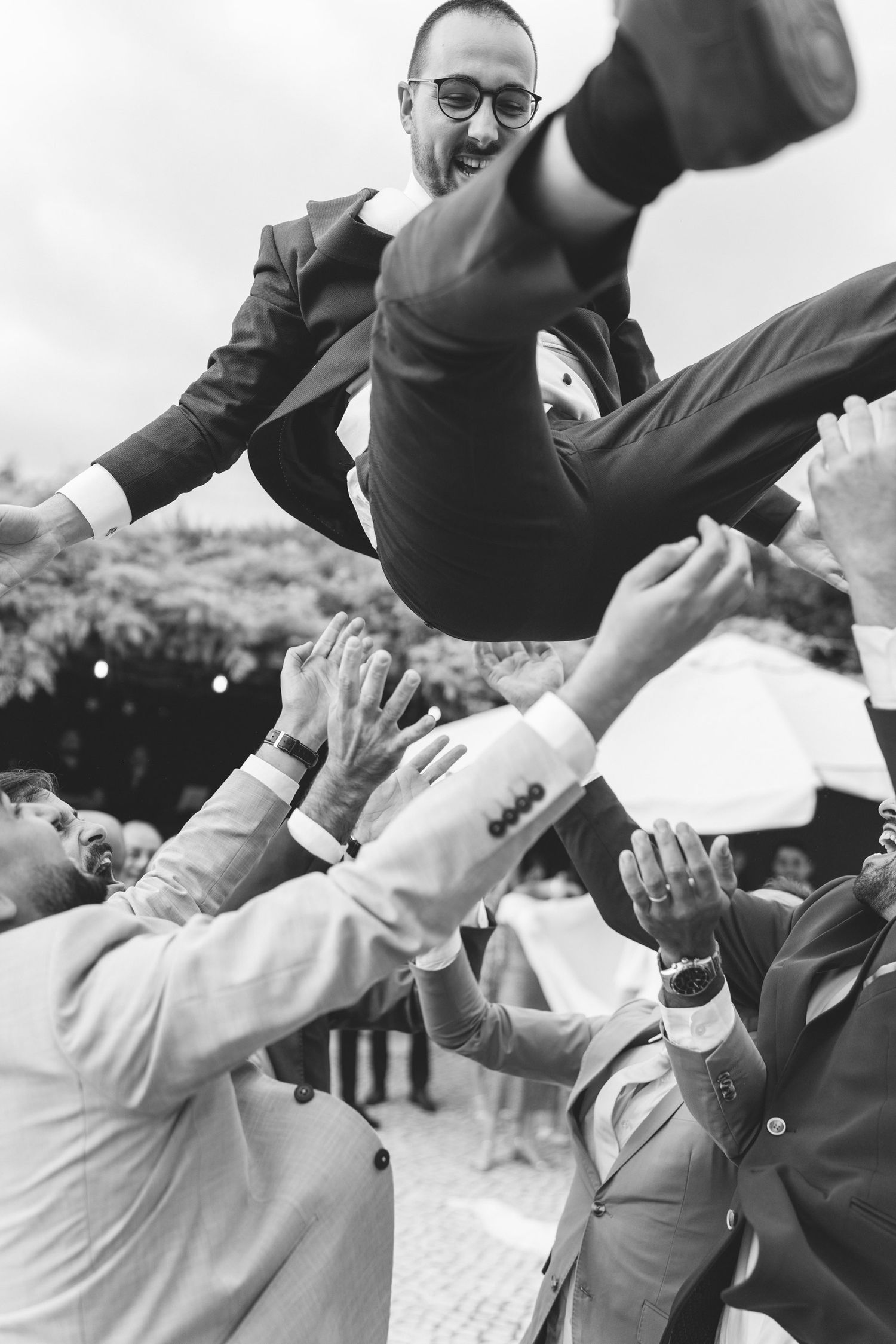 Black and white candid moment of the groom celebrating with wedding guests