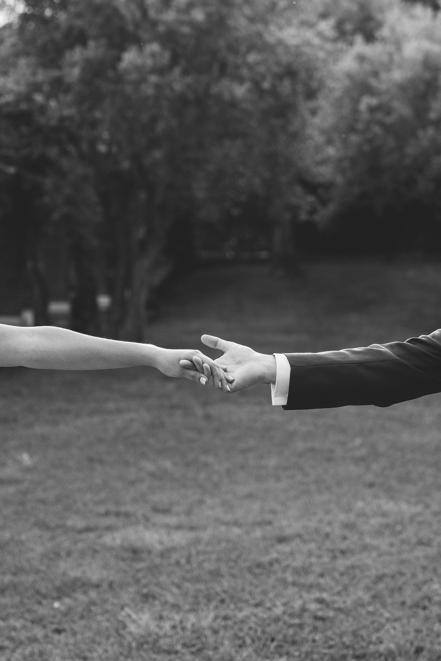 Black and white detail of bride and groom holding hands on their wedding day