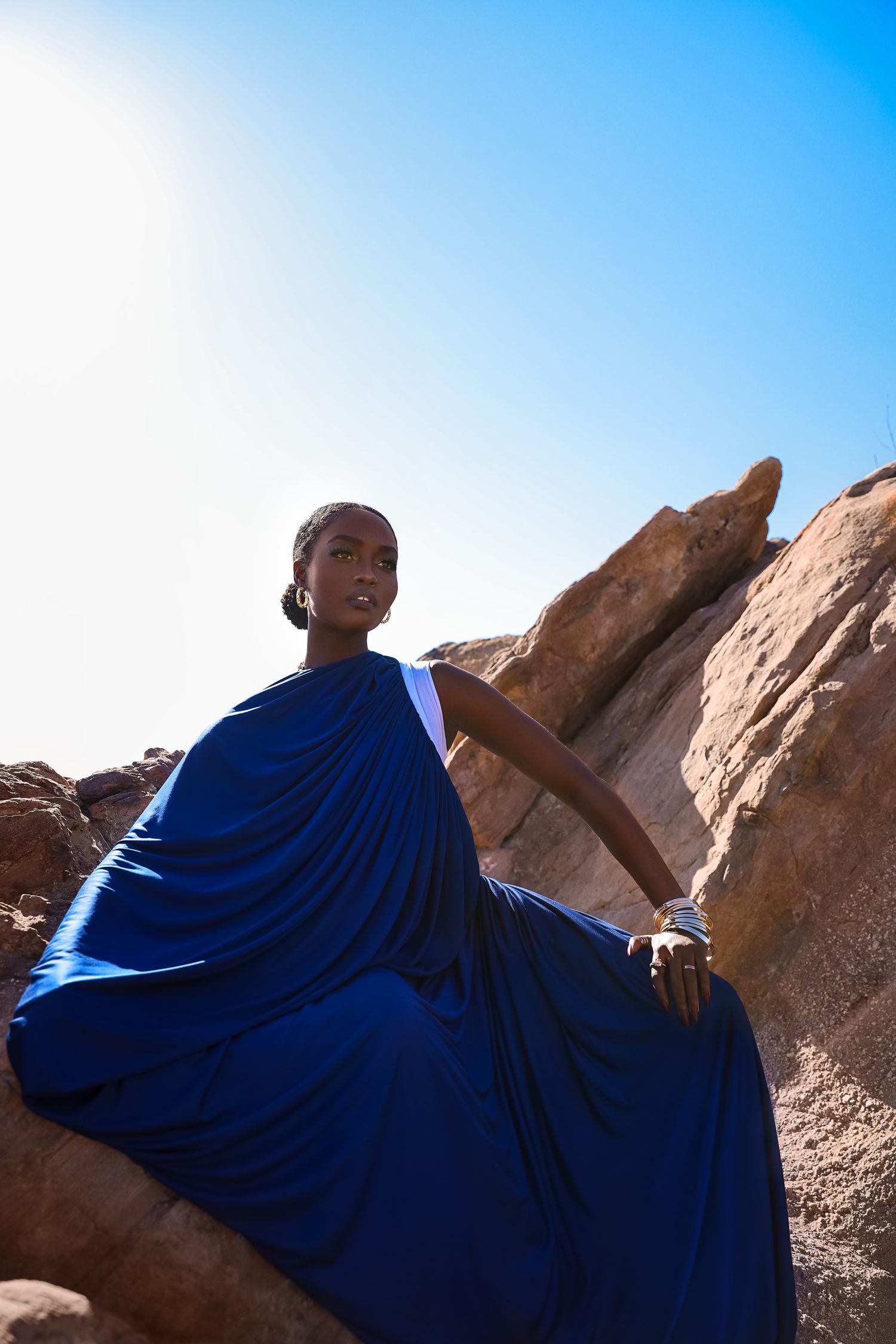 Figure in flowing blue fabric photographed against desert rock formations.  PZ STUDIO VISUALS