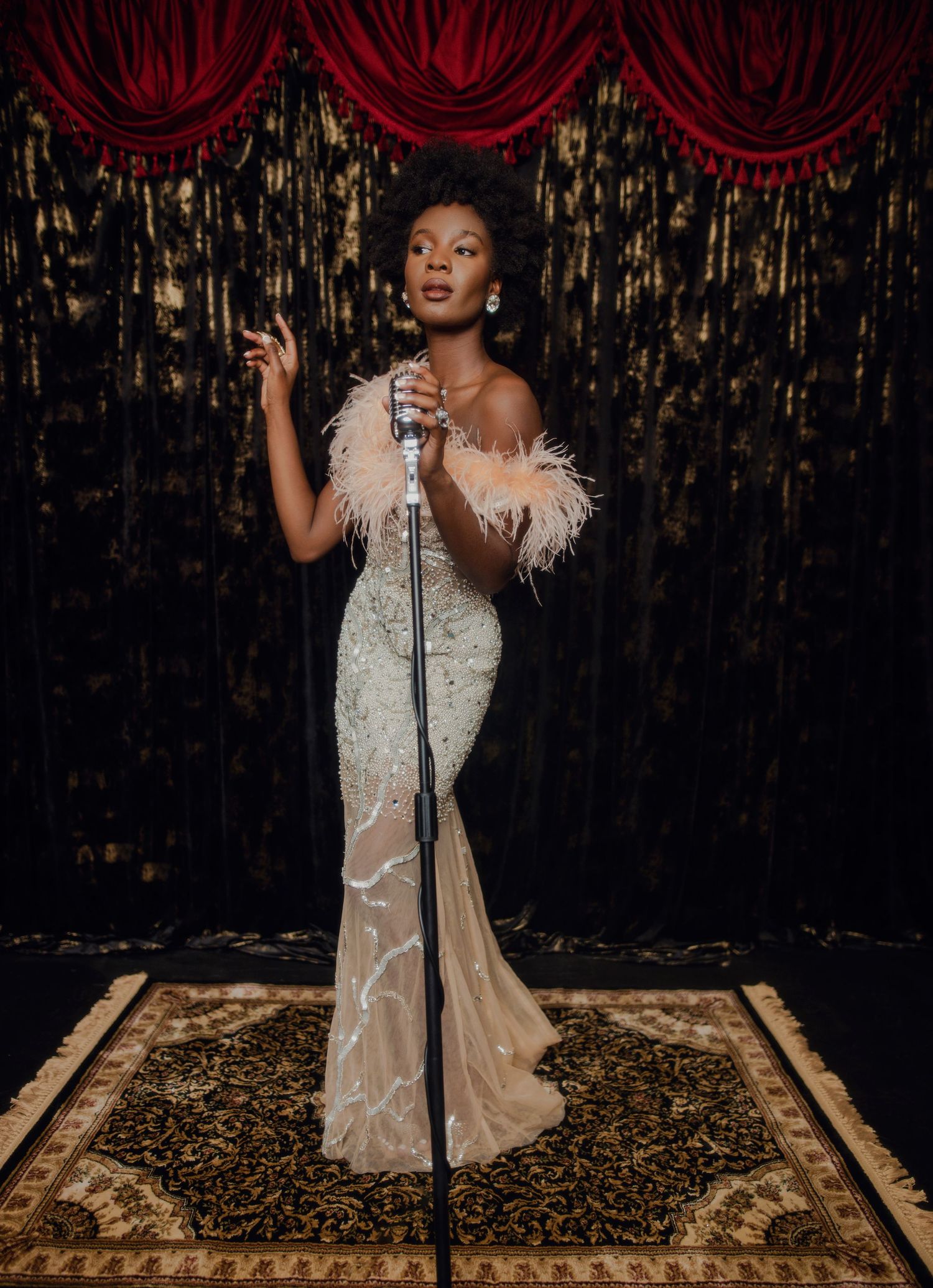 A performer in a glamorous beaded gown sings on stage with red curtains and gold decor. PZ STUDIO VISUALS