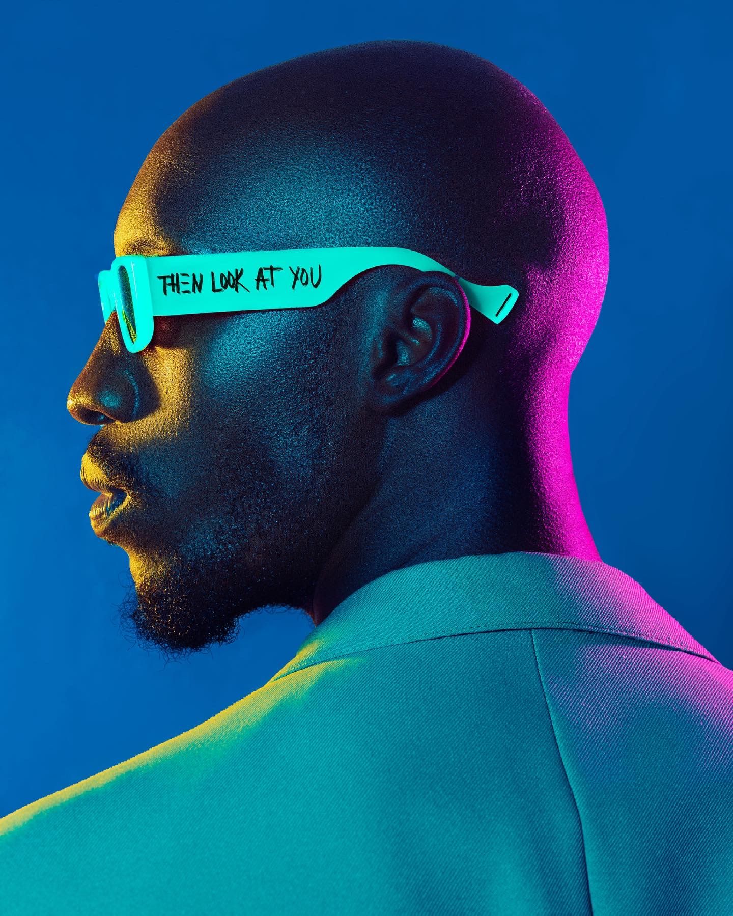 Profile portrait with glowing turquoise sunglasses against colorful gradient lighting. PZ STUDIO VISUALS