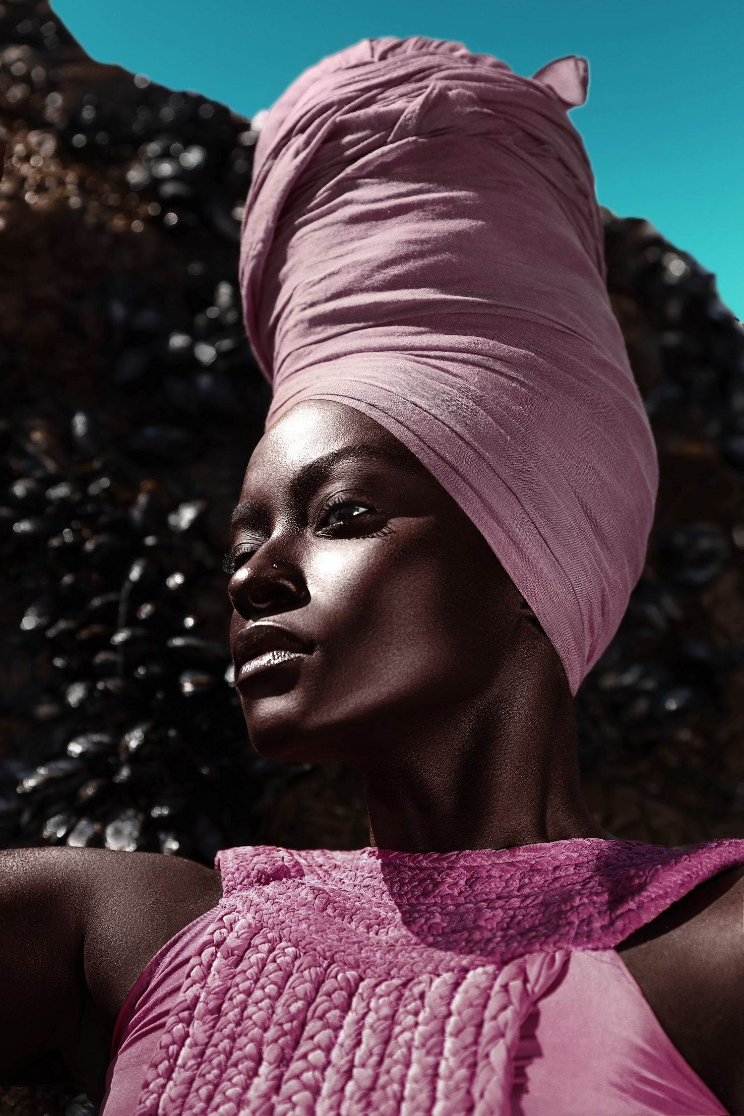 Artistic portrait with pink head wrap and matching dress against turquoise sky. PZ STUDIO VISUALS