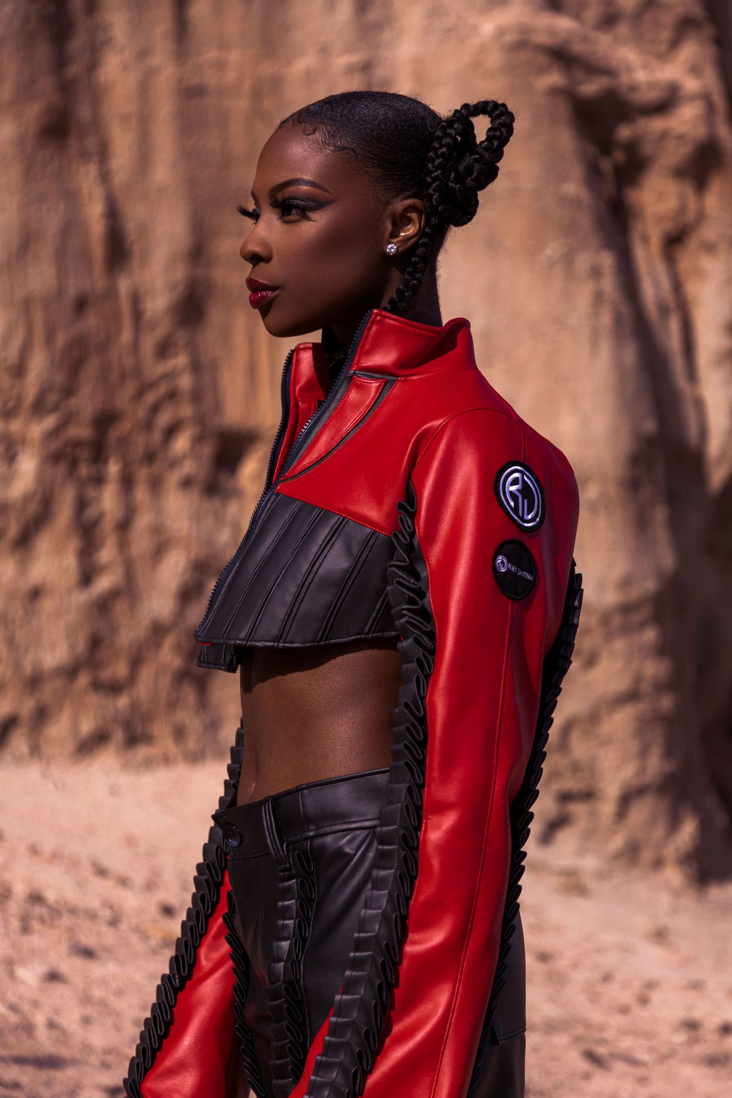 Fashion model wearing red and black edgy outfit poses against desert canyon backdrop. for Rey Jaiteh PZ STUDIO VISUALS
