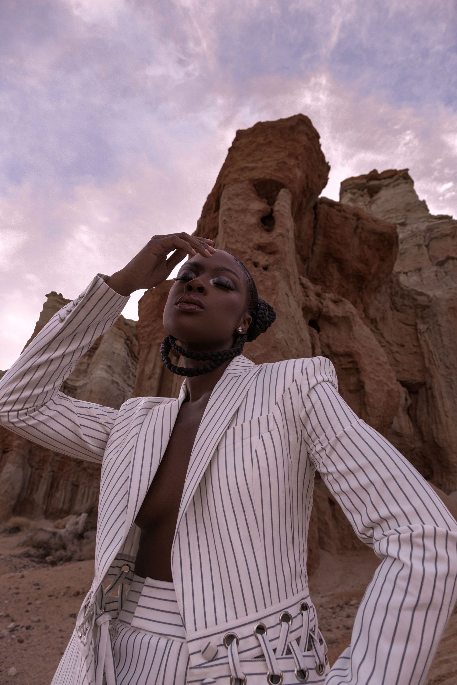 White pinstriped outfit styled against rugged desert cliffs during sunset. PZ STUDIO VISUALS
