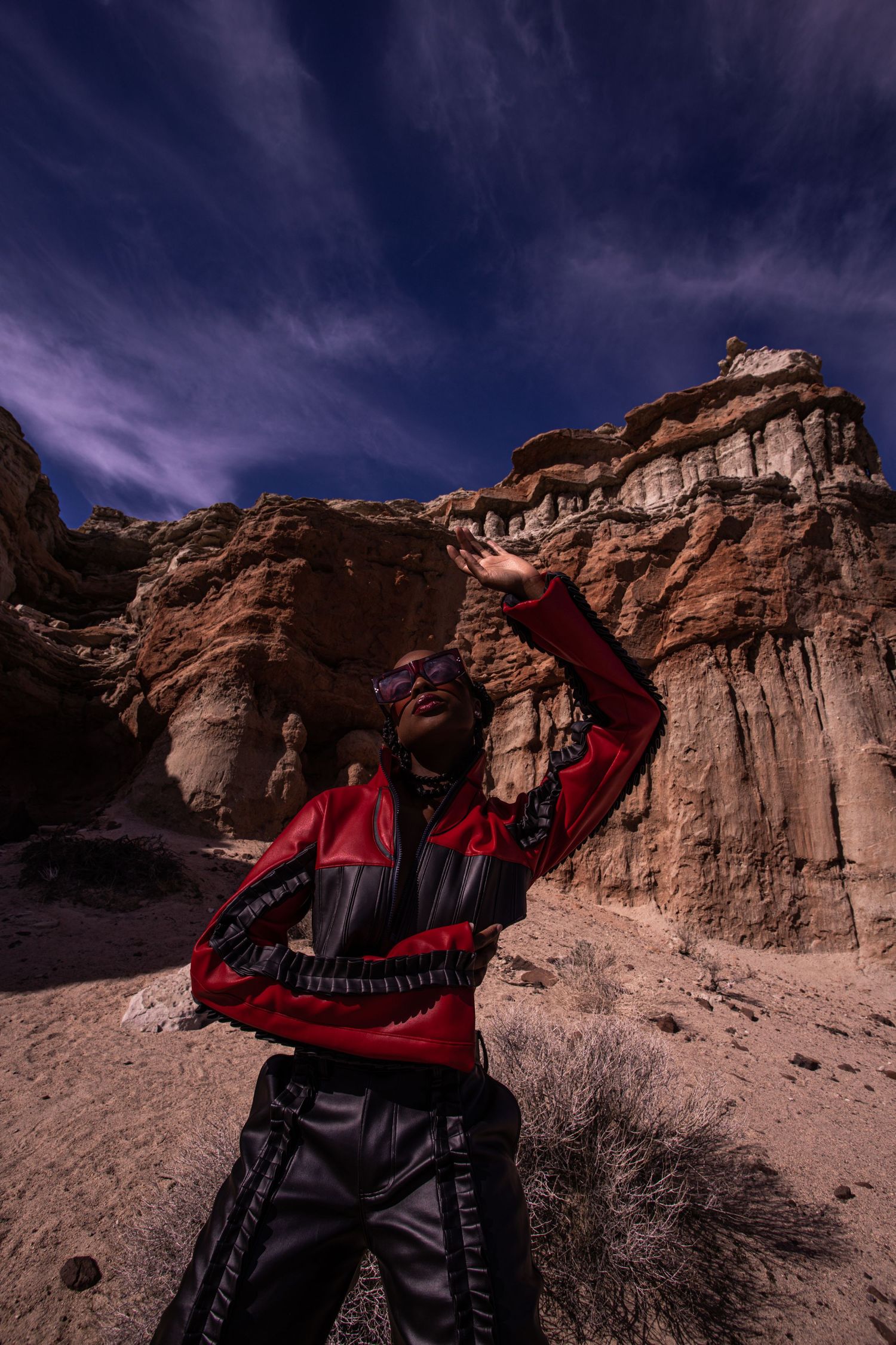 Fashion shoot in red and black attire against dramatic desert rock formations at dusk. for Rey Jaiteh PZ STUDIO VISUALS