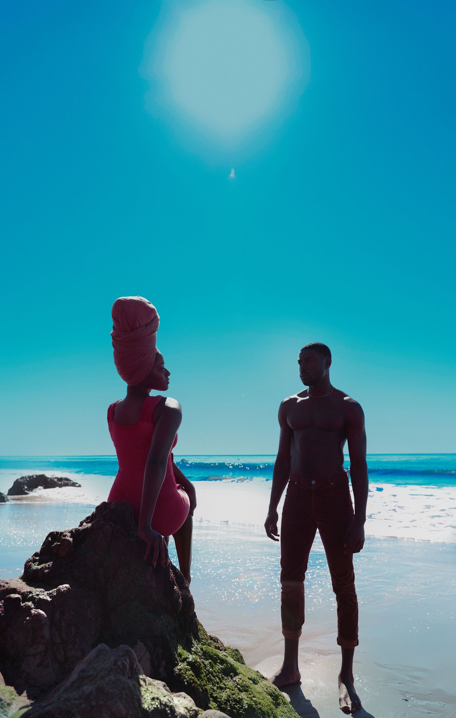 Silhouettes of people enjoying a sunny day at the beach against bright blue sky and ocean waves. PZ STUDIO VISUALS