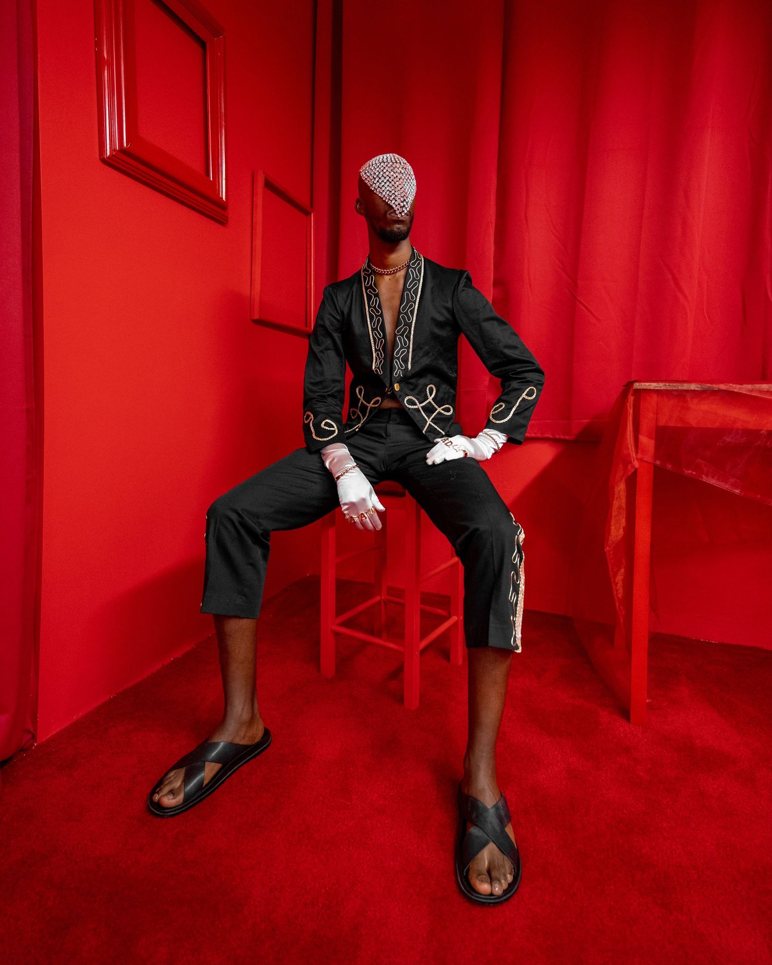 A person sits in a chair against a vibrant red wall, creating a striking minimalist composition. Photo by Kyler James PZ STUDIO VISUALS