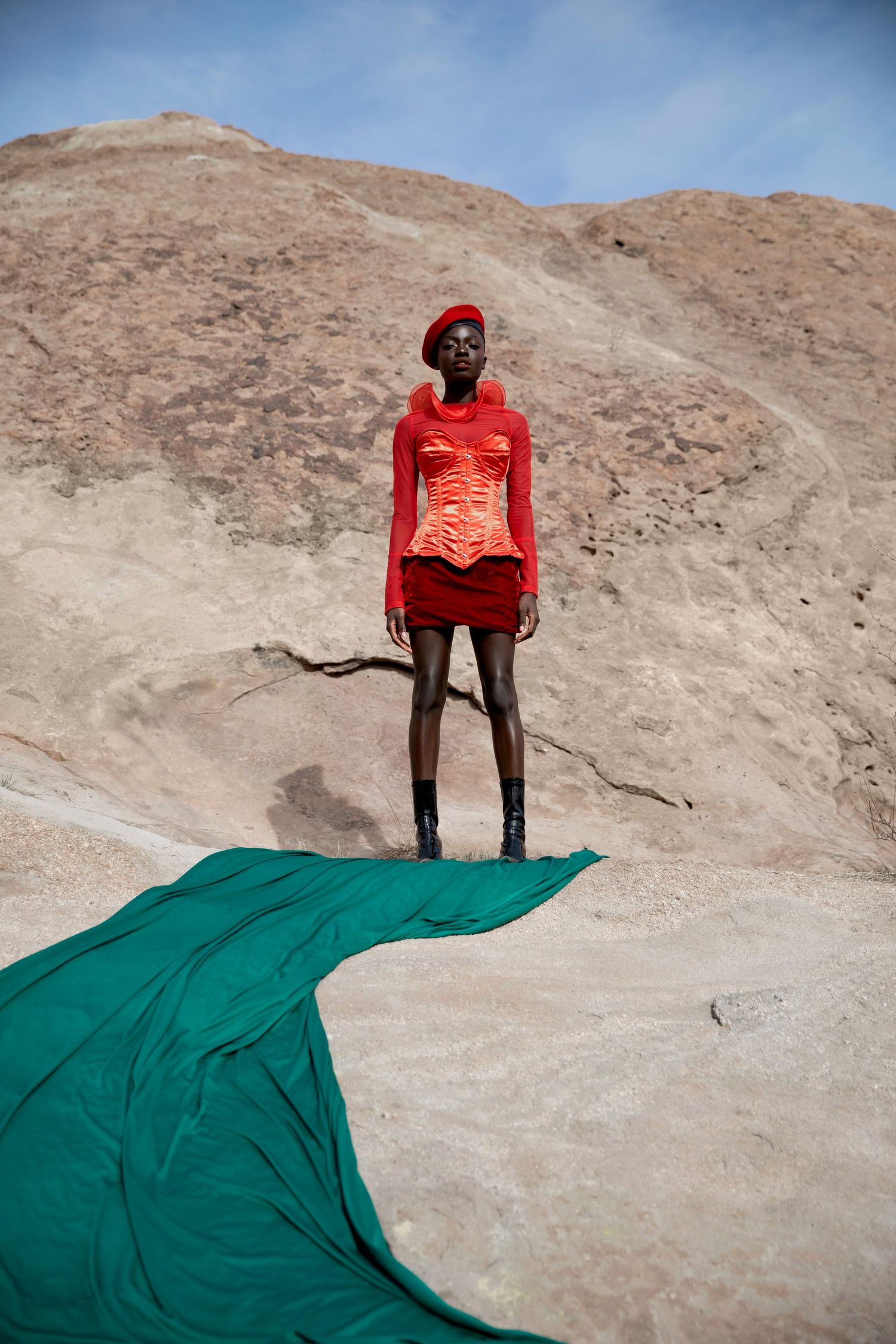 Person in red shirt stands on rocky terrain with flowing teal fabric creating dramatic contrast against desert landscape. PZ STUDIO VISUALS