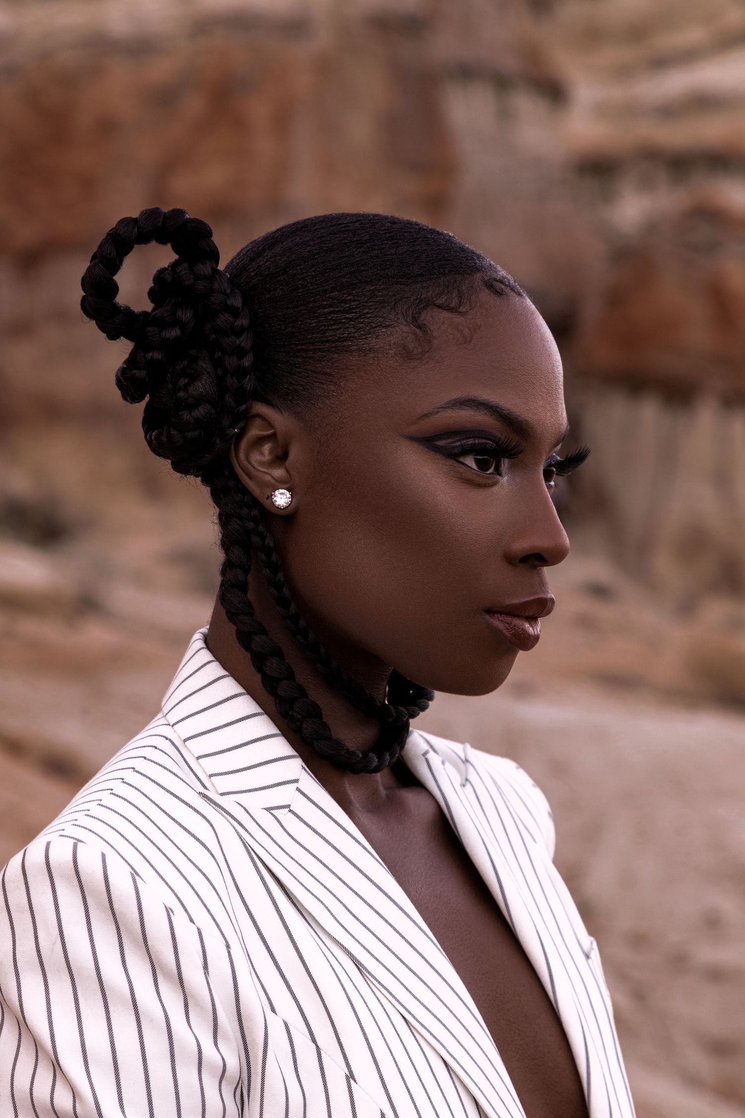 Fashion portrait with braided updo and striped blazer against desert backdrop. PZ STUDIO VISUALS
