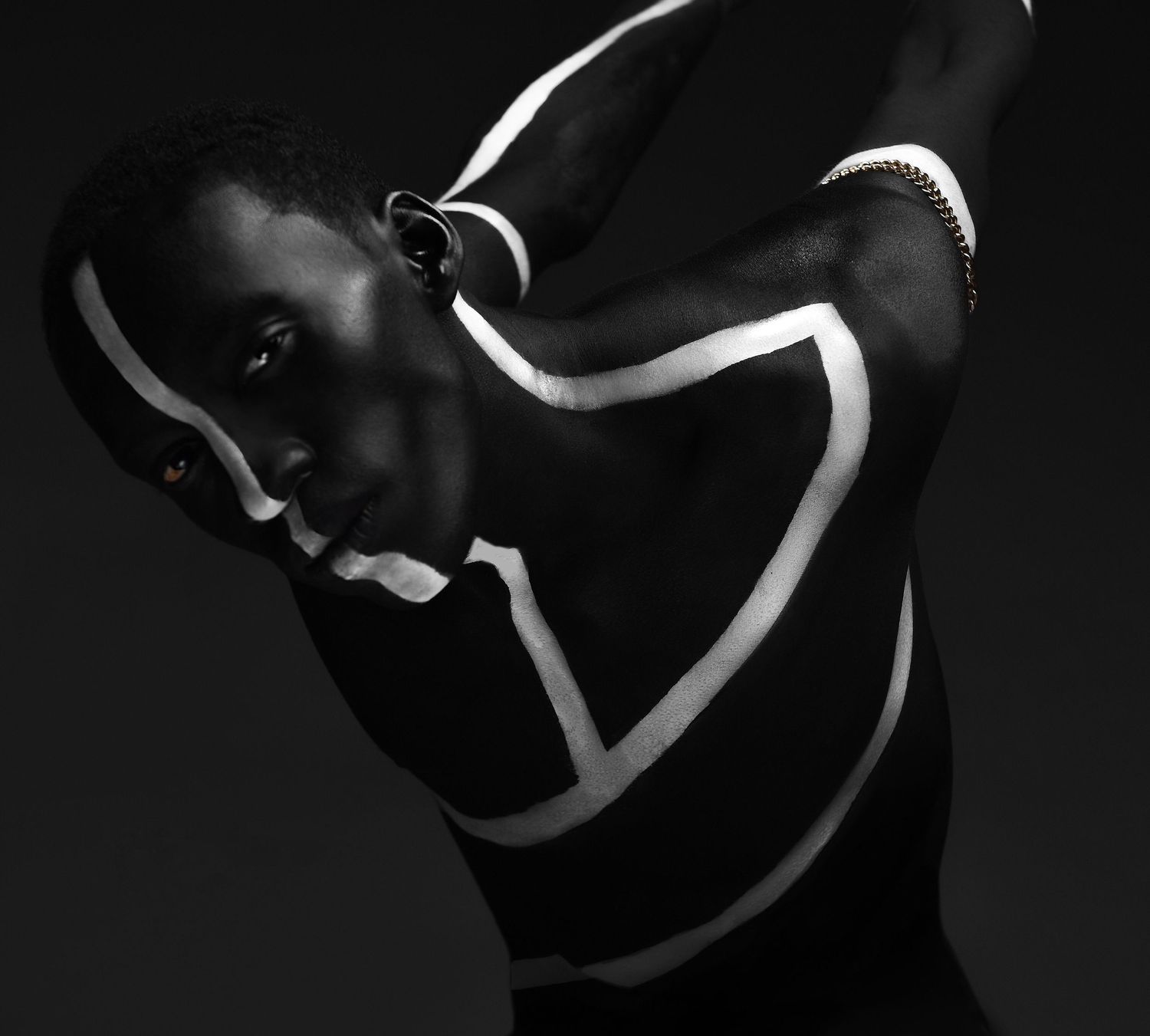 Black and white artistic portrait with white body paint lines creating geometric patterns. PZ STUDIO VISUALS
