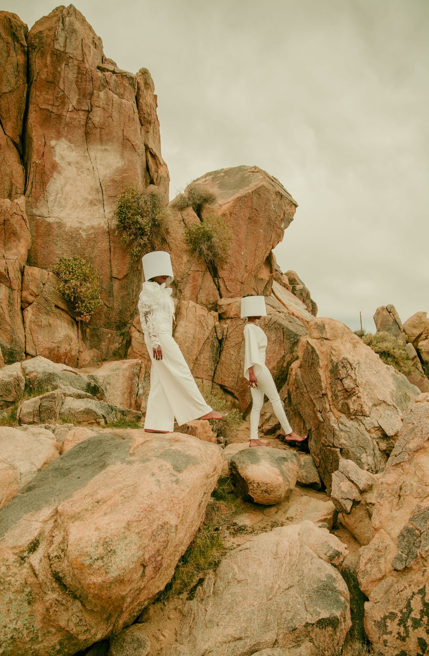 White fabric sculptures positioned on rocky desert terrain against cloudy skies. PZ STUDIO VISUALS