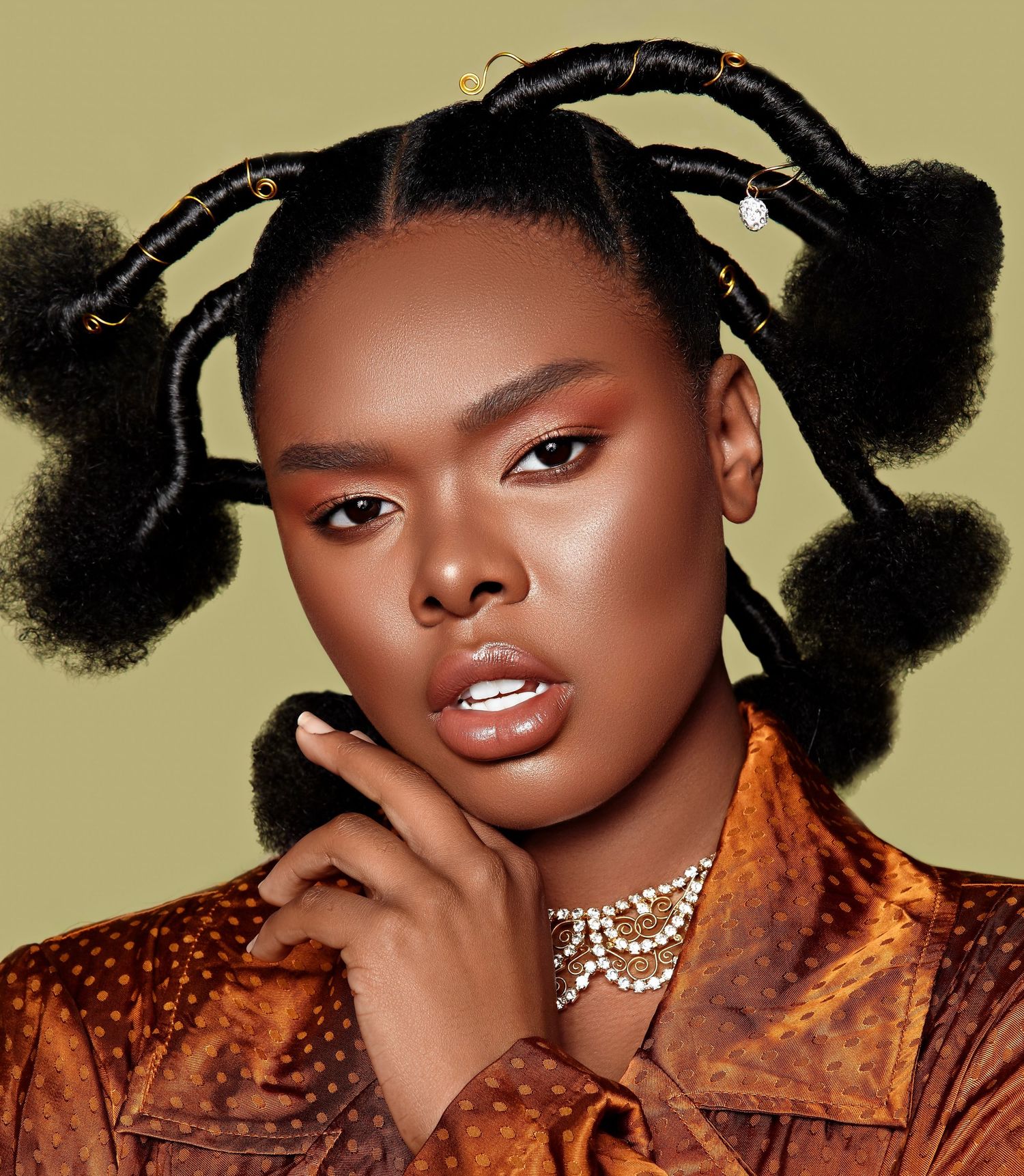 Fashion portrait with creative hairstyle, orange velvet top and sparkling necklace against olive background. PZ STUDIO VISUALS