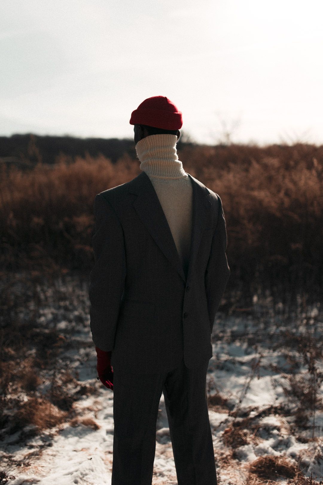 A silhouetted figure in a suit and red cap stands in a misty winter landscape. PZ STUDIO VISUALS