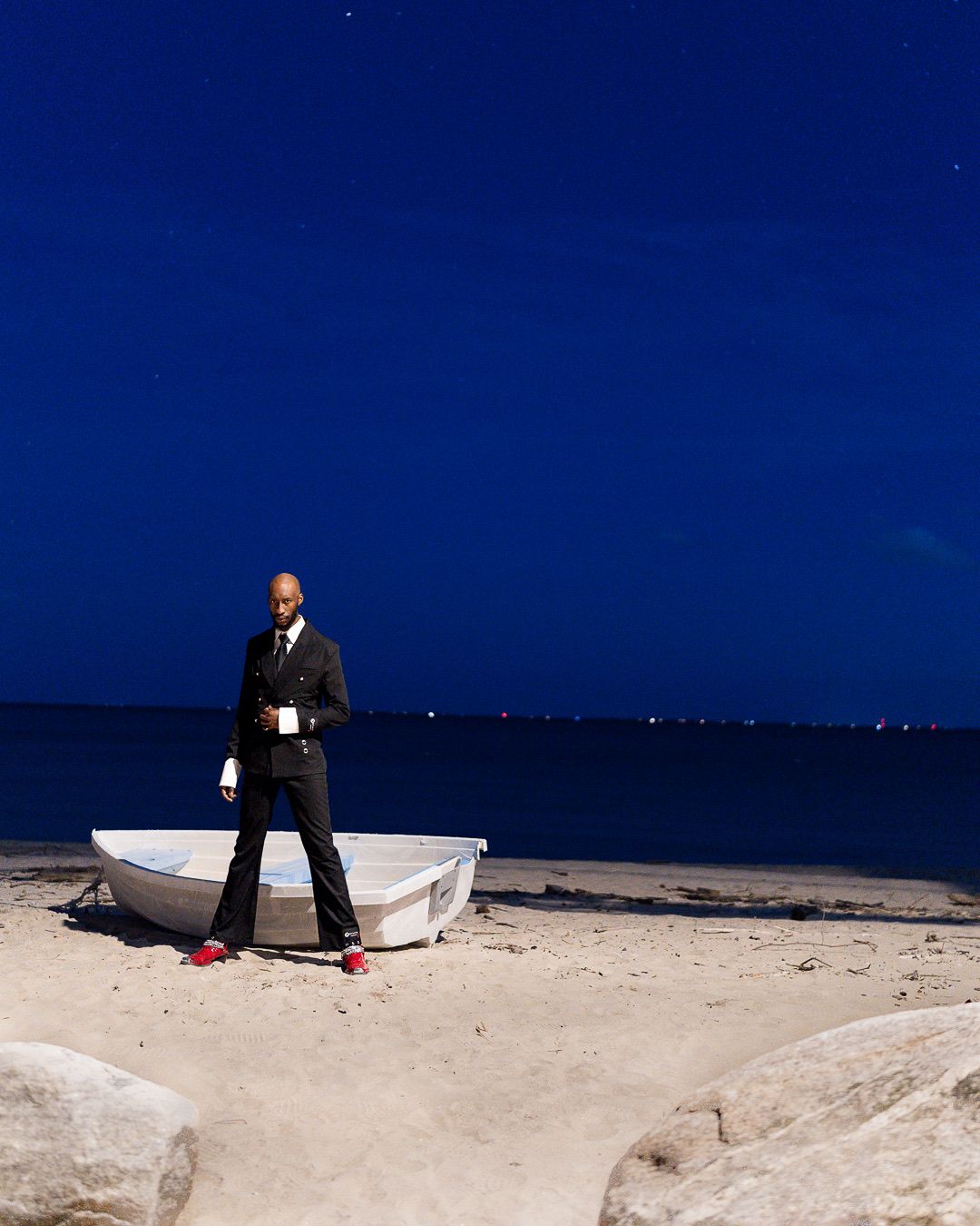 A sequence of four photos shows someone sitting on a white boat against a deep blue sky and sandy beach backdrop.