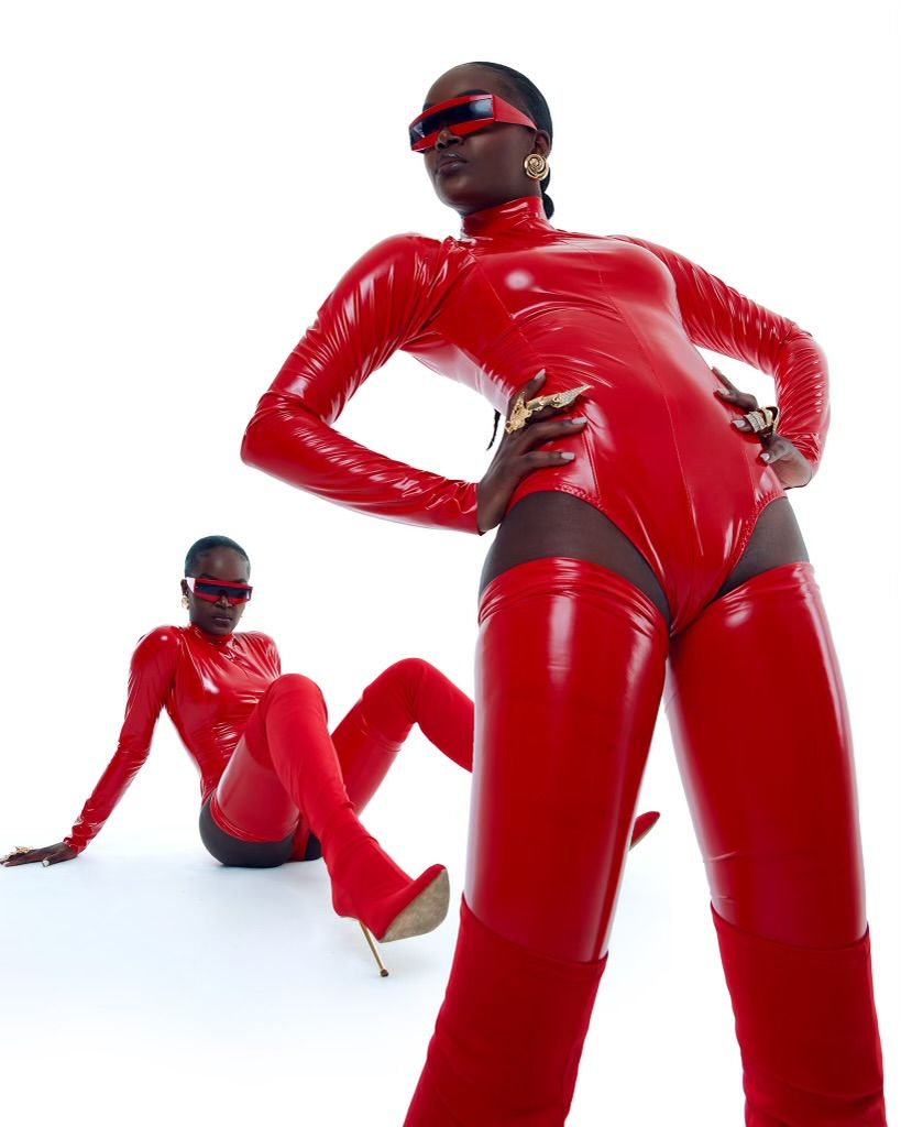 Two models in striking red latex bodysuits and sunglasses pose dramatically against white background. PZ STUDIO VISUALS
