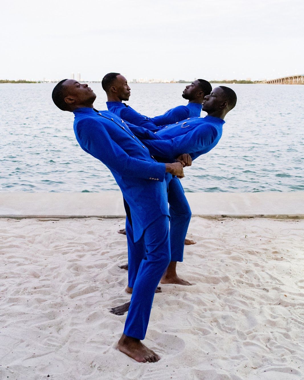 Playful beach portraits of couple in matching bright blue outfits on white sand. PZ STUDIO VISUALS