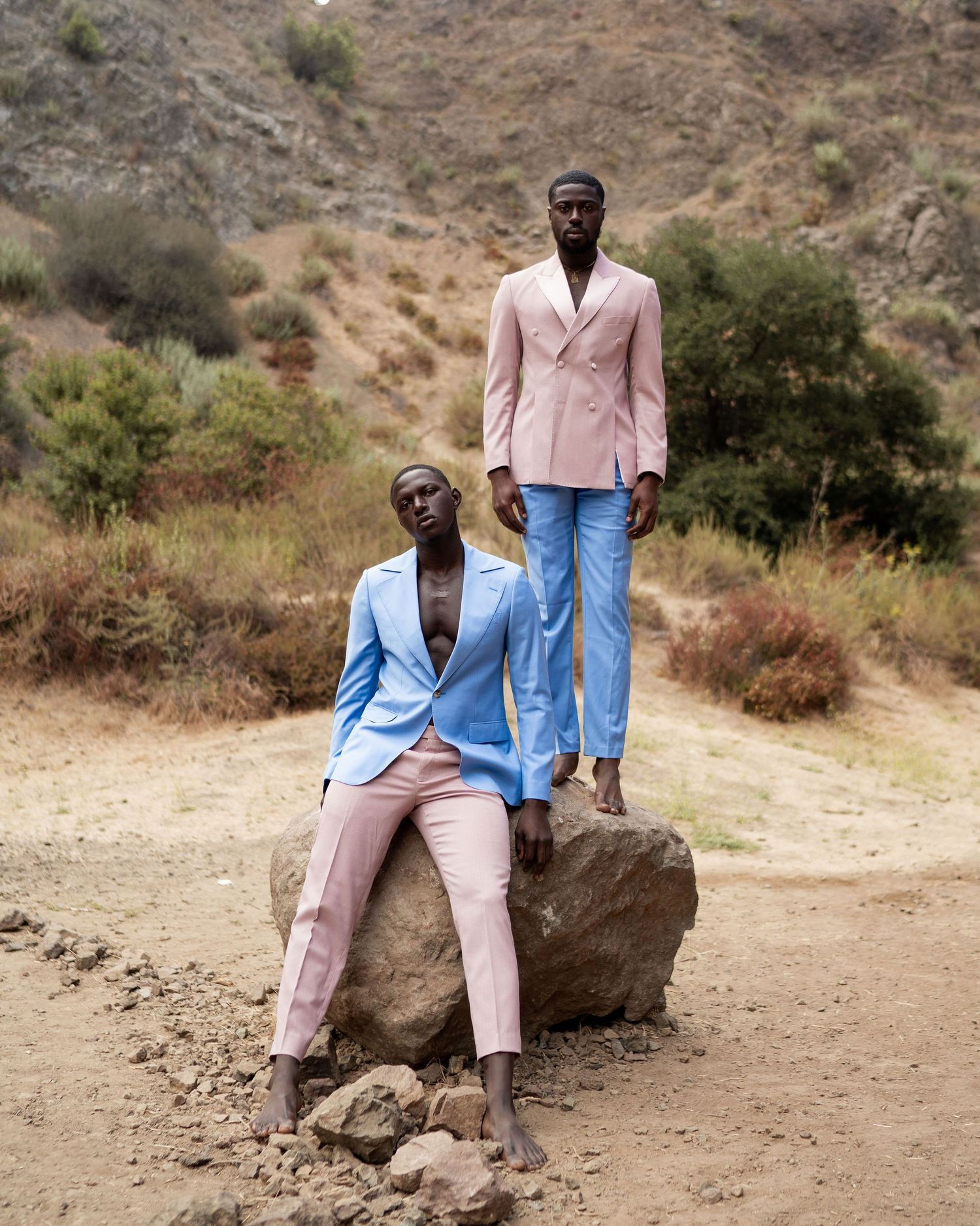 Fashion editorial shoot in pastel suits against a rugged desert hillside backdrop. PZ STUDIO VISUALS