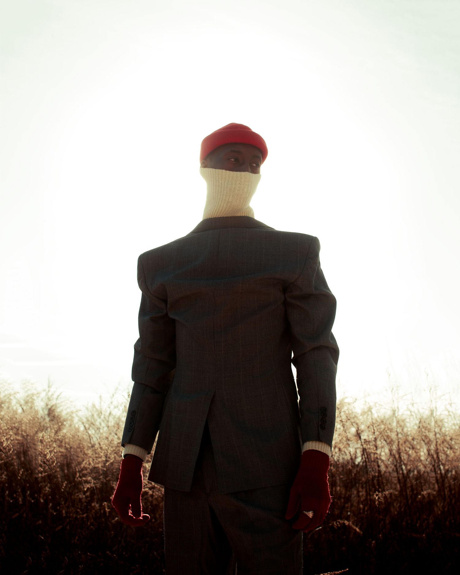 A silhouetted person in a suit and red cap stands against a bright white background at sunset. PZ STUDIO VISUALS
