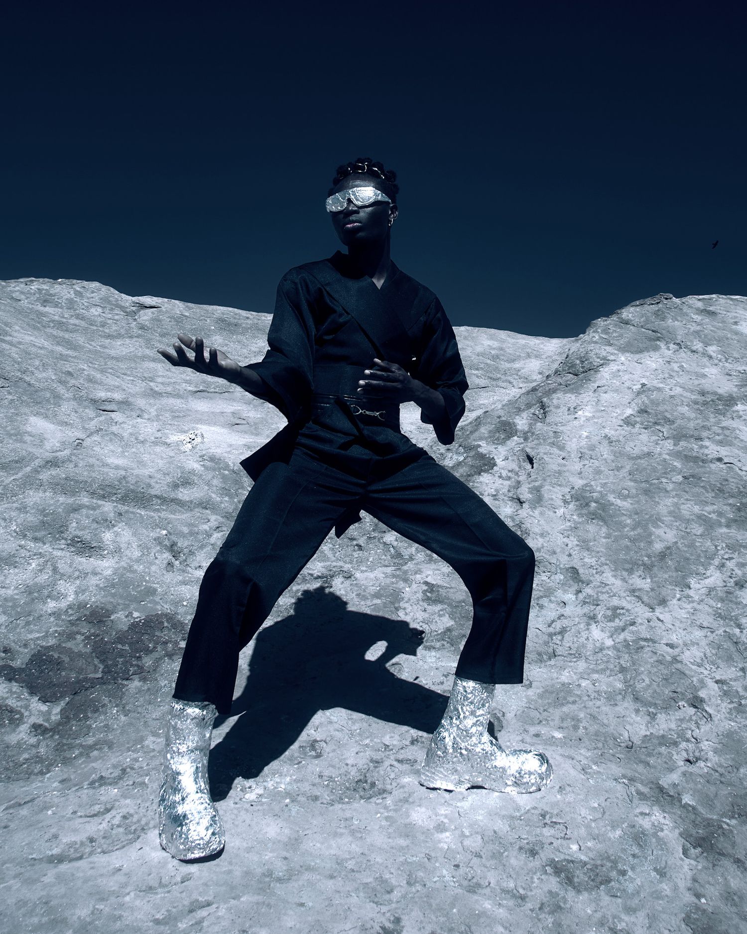Figure in dark clothing creates dynamic poses against stark white landscape. Isaak Adoyi. PZ STUDIO VISUALS