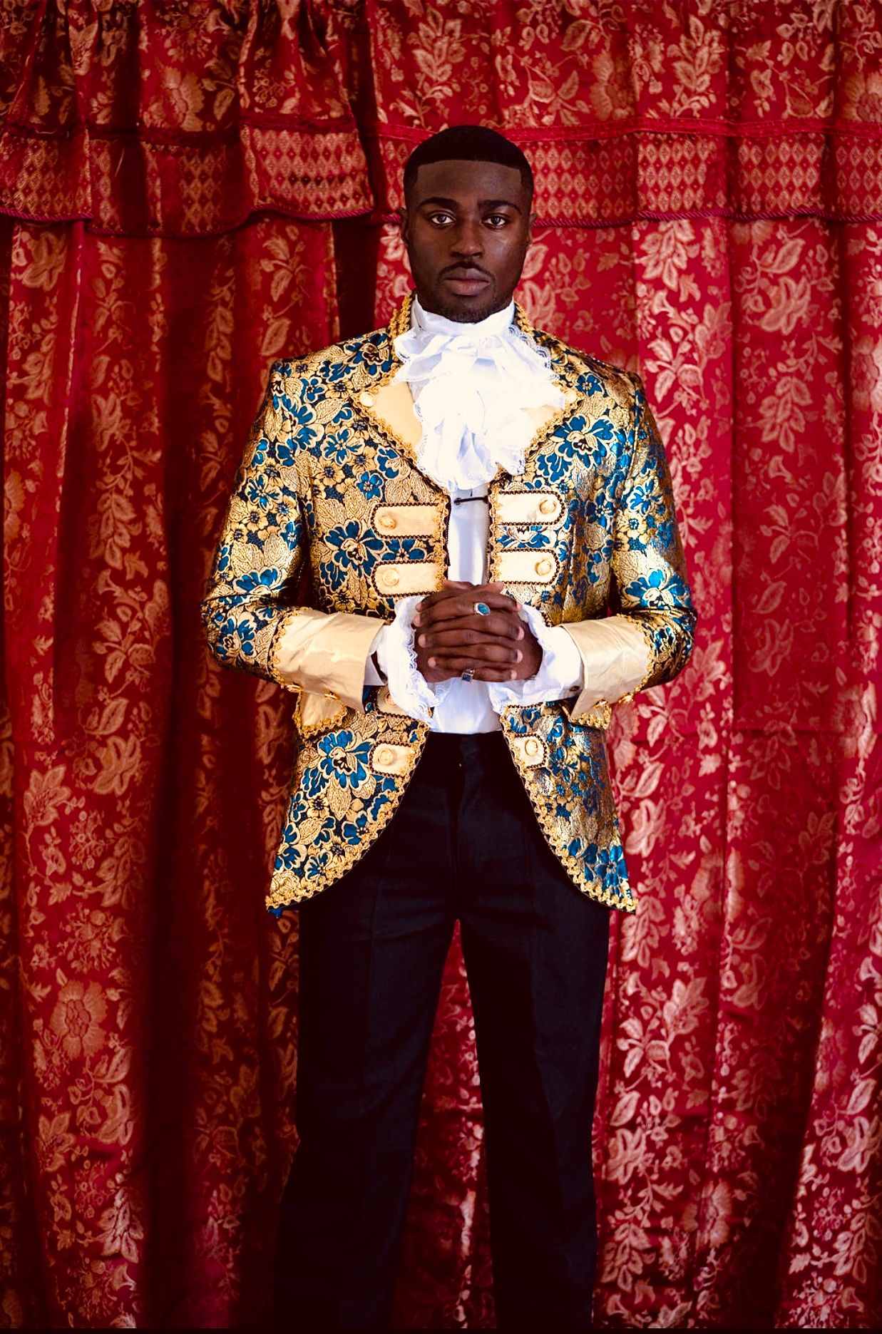 Person wearing ornate gold and turquoise embroidered jacket poses against red curtain backdrop in sequential photos. PZ STUDIO VISUALS