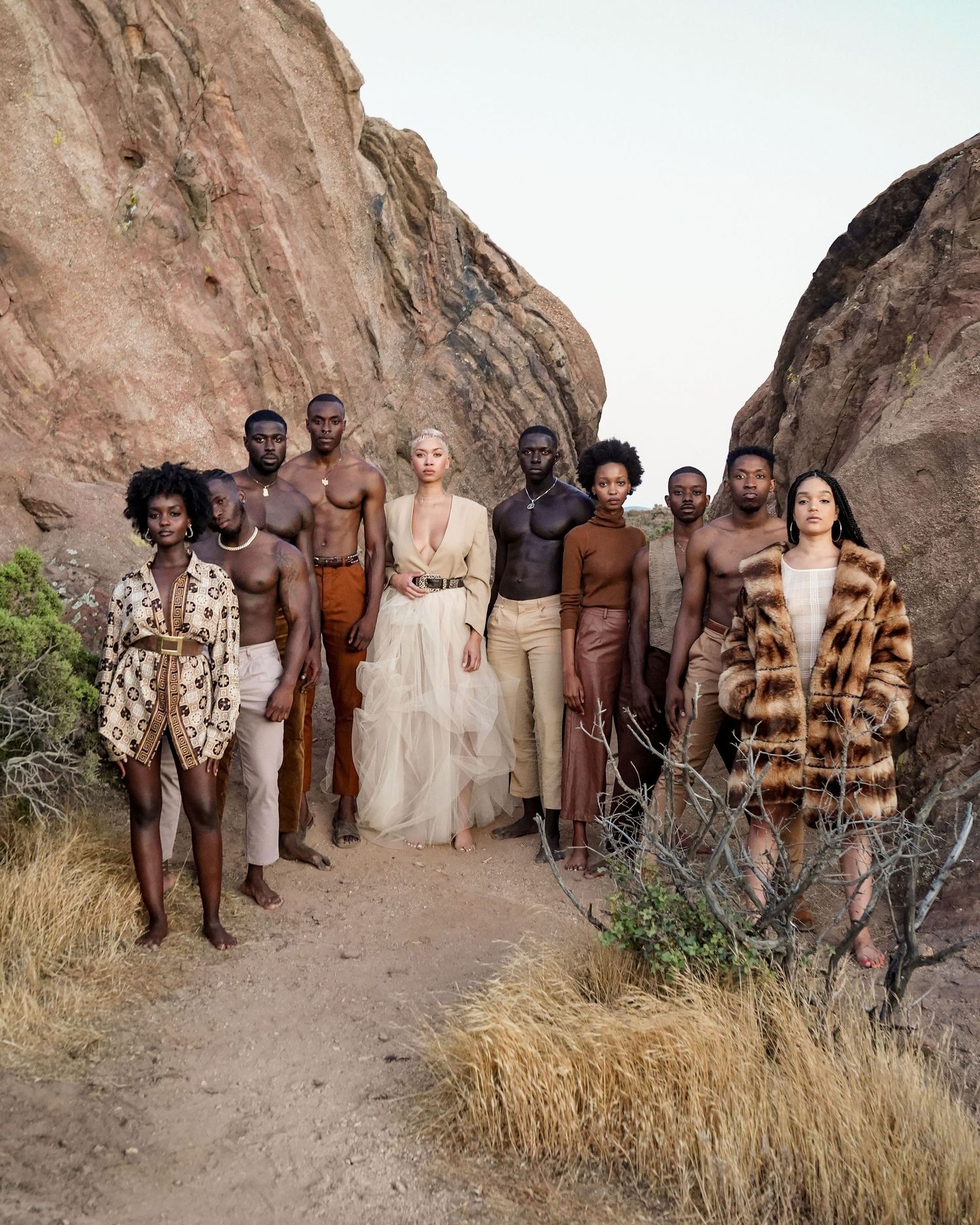 Group photo of people wearing earth-toned outfits standing against a rocky desert backdrop.PZ STUDIO VISUALS