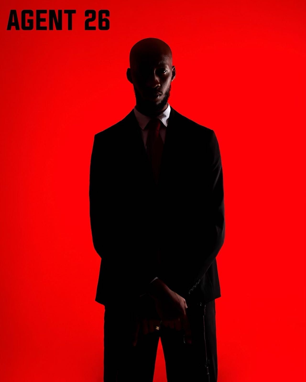 Dark silhouettes of suited figure against bright red background with text. PZ STUDIO VISUALS Agent 47 now AGENT 26 - A NEW DAWN