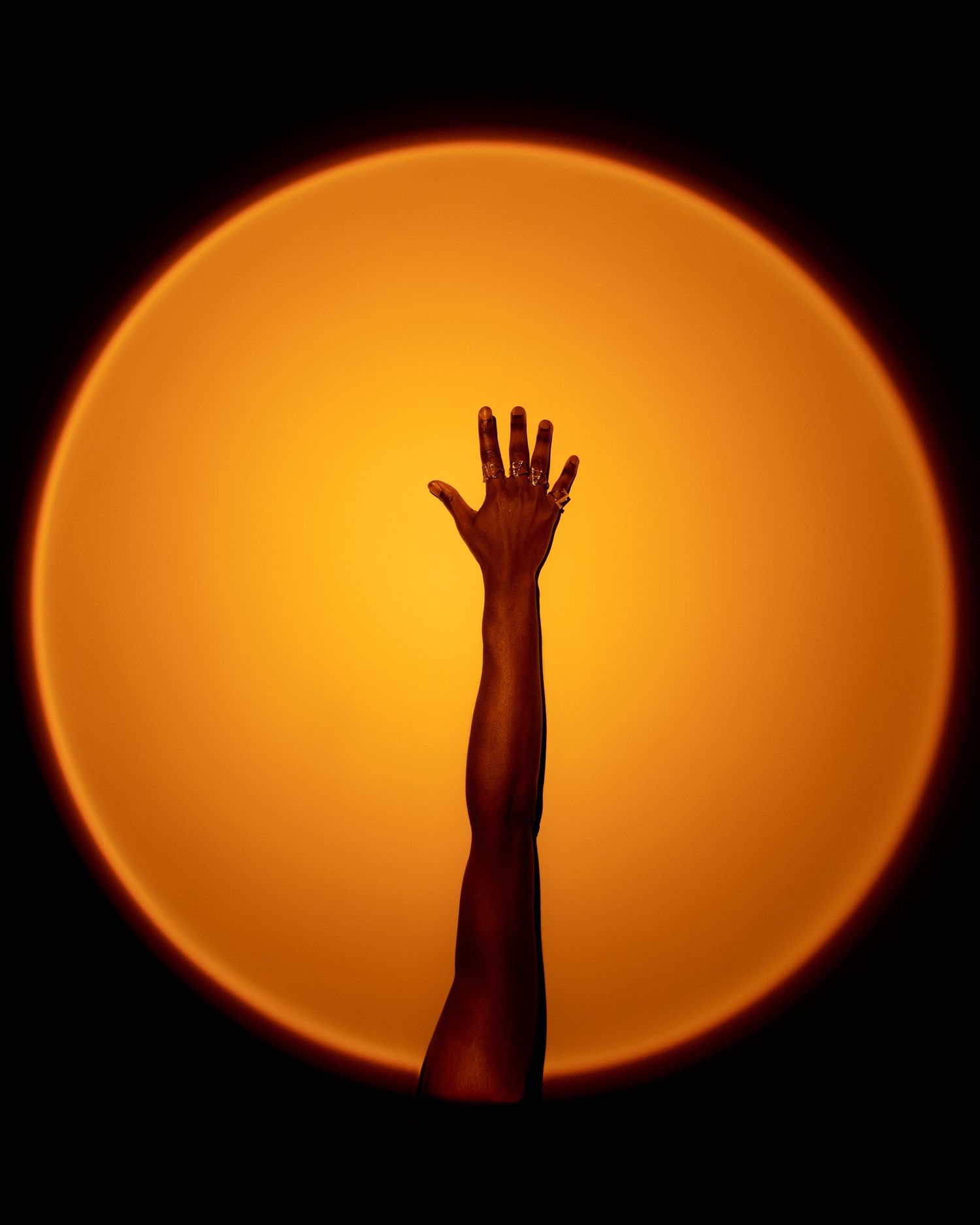 Dramatic sequence of a hand reaching up against an orange circular light. PZ STUDIO VISUALS