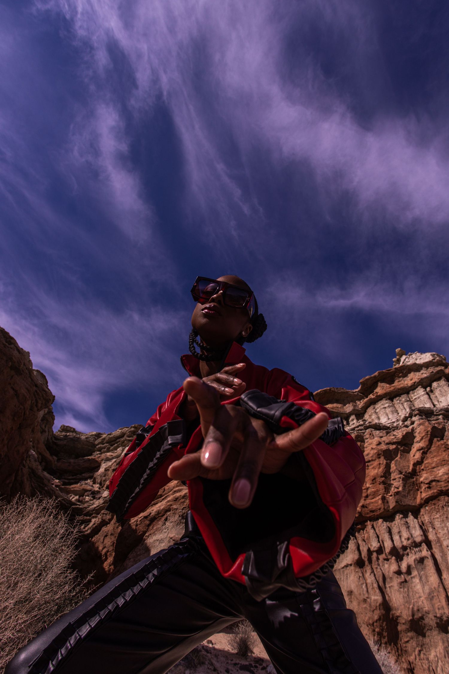 Dramatic low angle shot against purple stormy sky with figure in red cape on rocky terrain. PZ STUDIO VISUALS