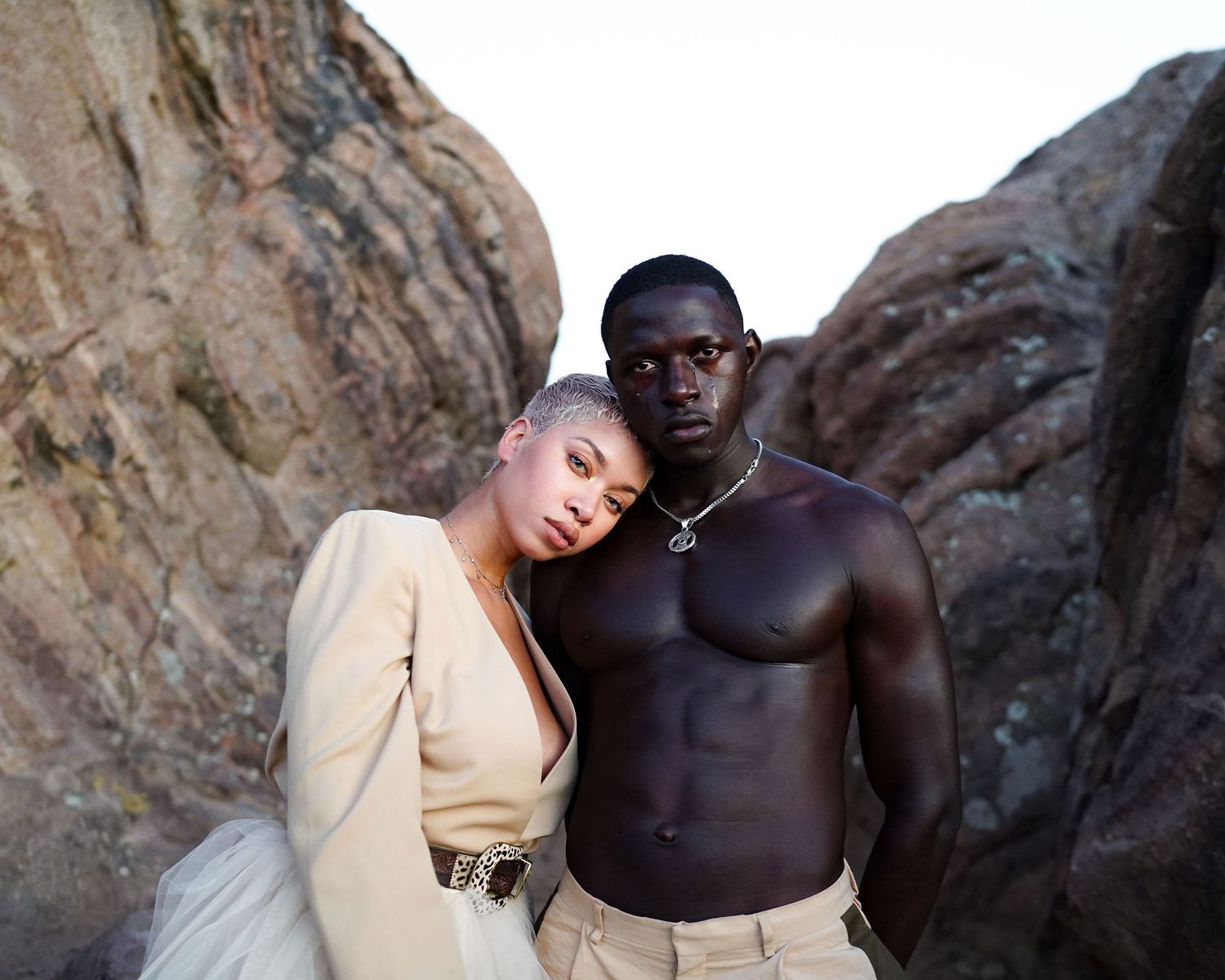 Two figures pose artistically against rocky cliffs in contrasting light and dark outfits. PZ STUDIO VISUALS