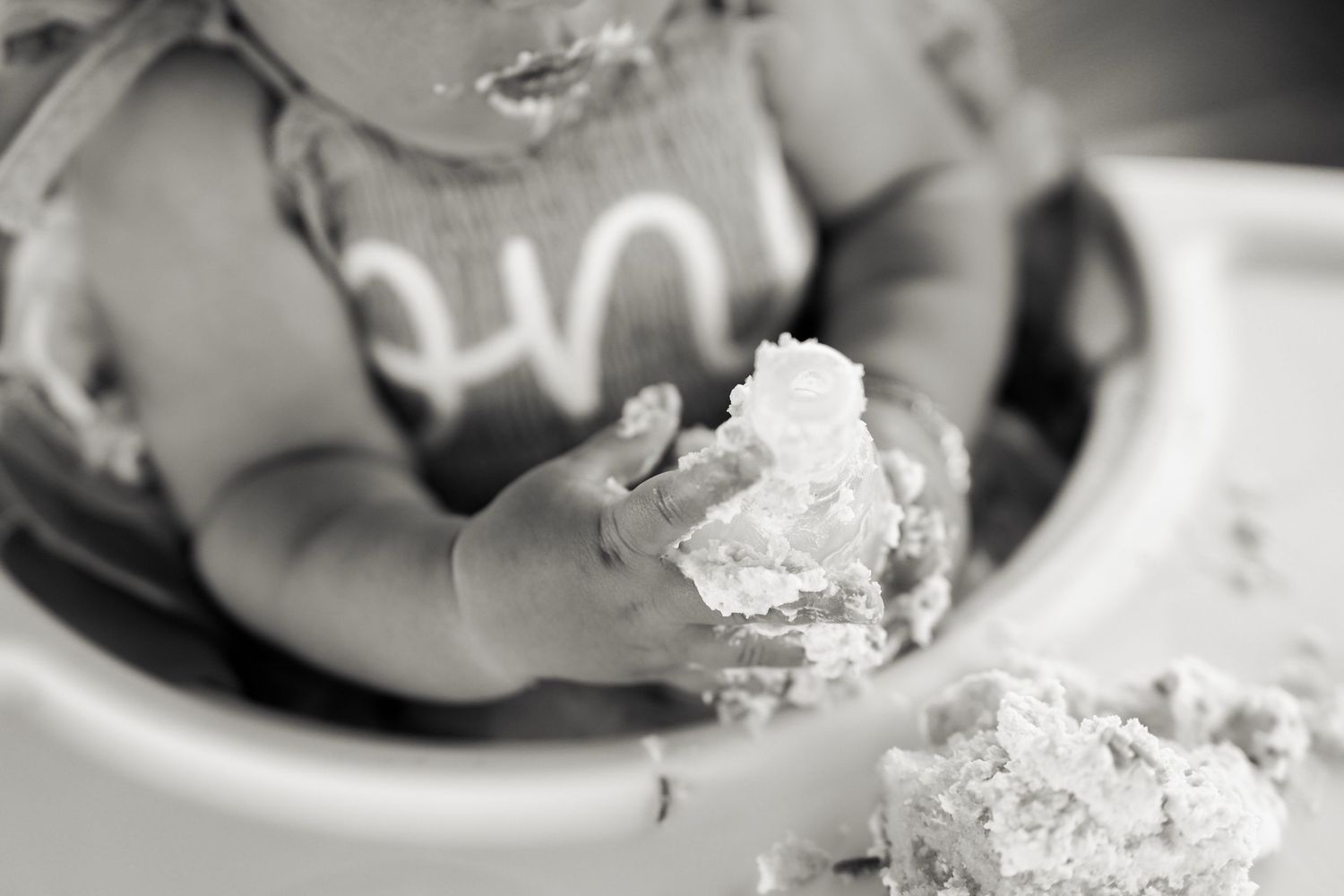 Black and white photos of child with birthday cake during smash cake session.