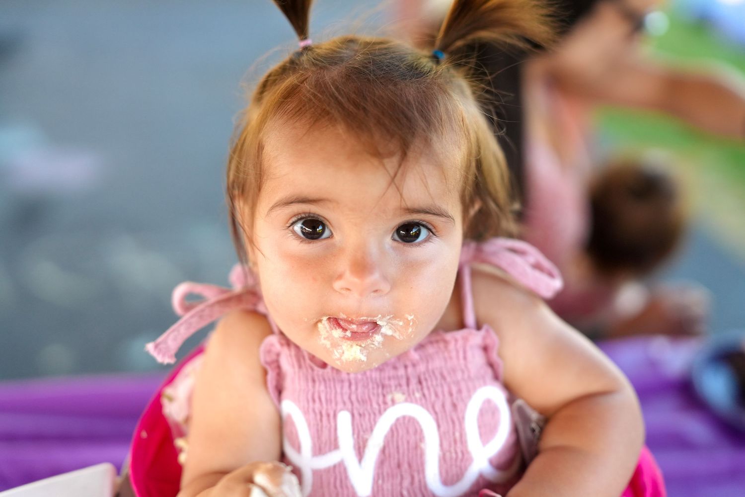 Child enjoying cake smash photoshoot with colorful decorations.