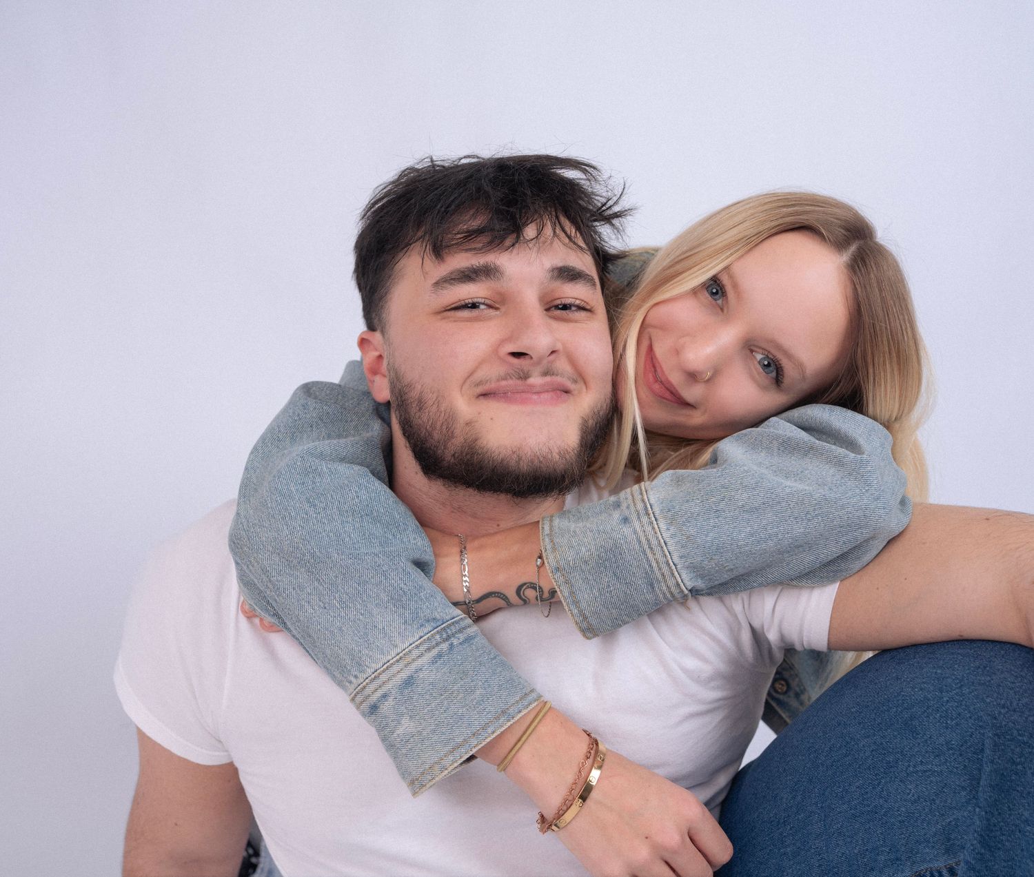 A casual portrait of a couple in denim and white shirts sharing an affectionate moment.