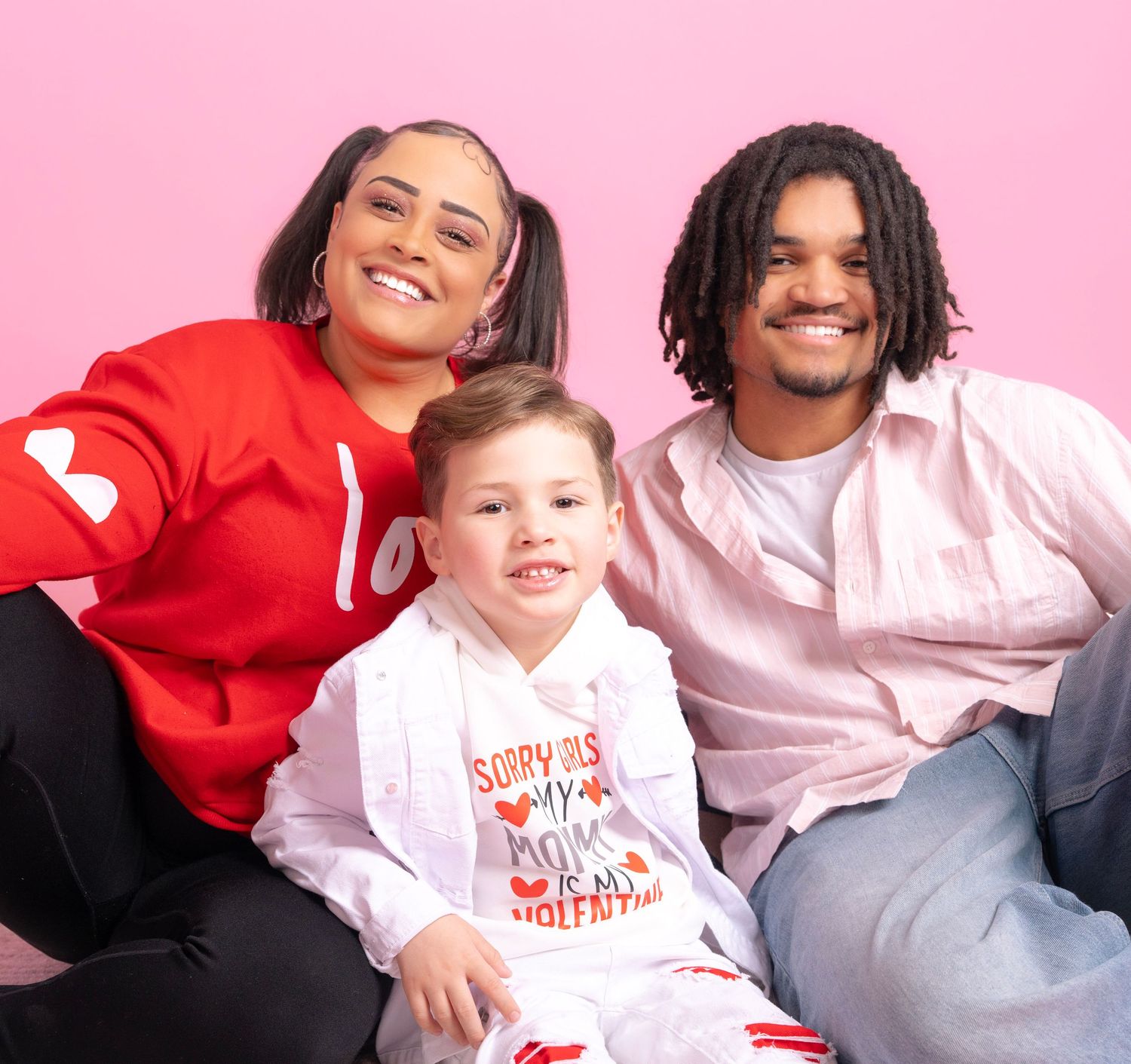 Family photoshoot with pink background showing playful moments and matching outfits.