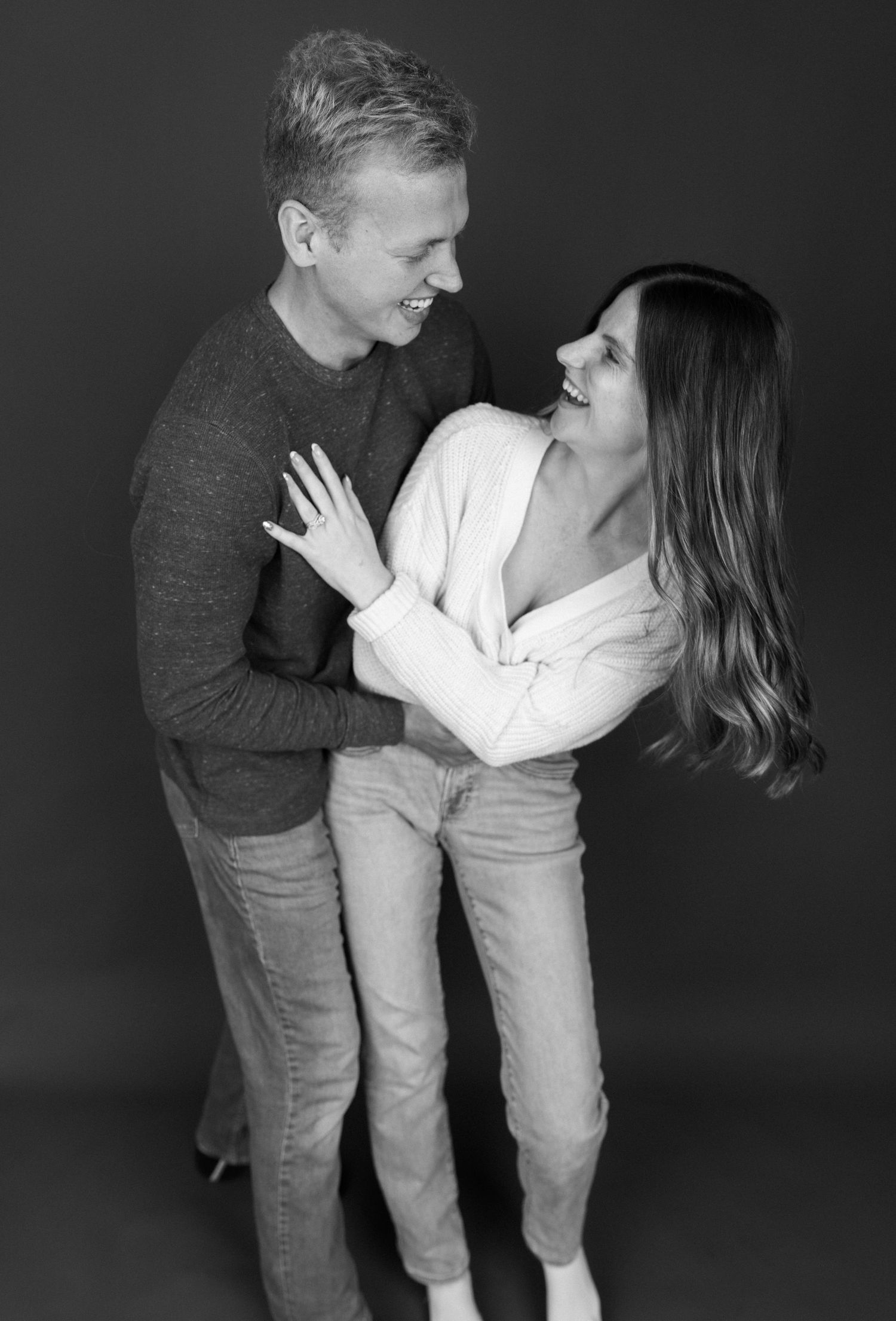 An intimate black and white portrait of a couple in casual clothing sharing a loving moment.