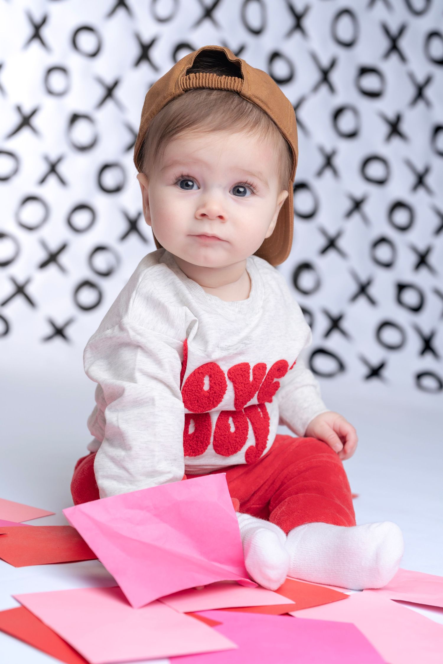 Valentine's themed baby photos with XO pattern background and pink hearts.