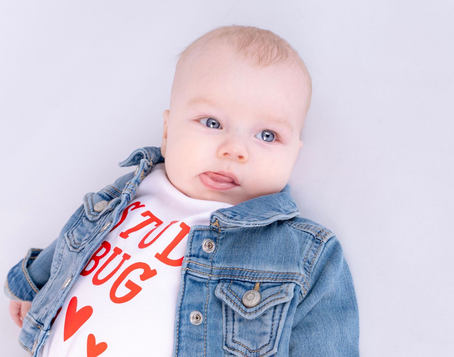 Baby wearing denim jacket and heart print shirt in series of close-up shots.