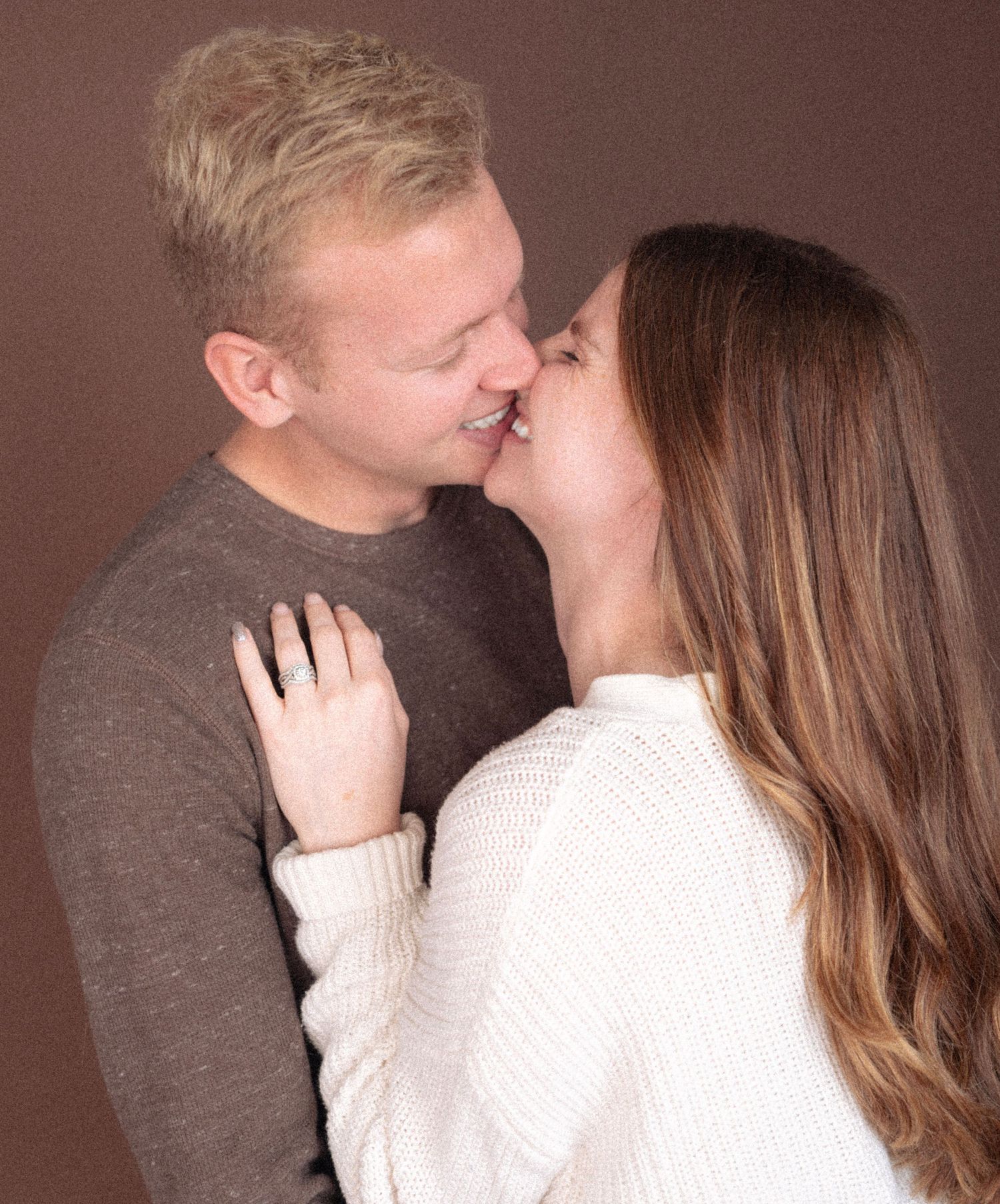 A romantic close-up portrait of a couple about to kiss, wearing neutral colored sweaters.