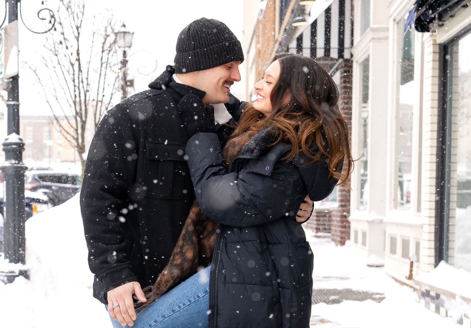 Couple sharing romantic moment in snowy winter street scene.