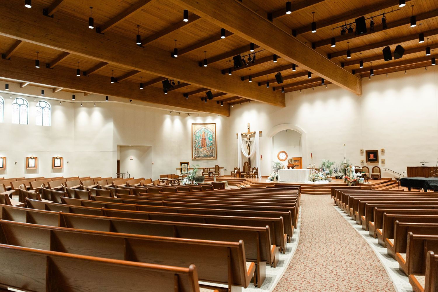 Interior view of a modern church sanctuary with wooden beams and rows of pews.