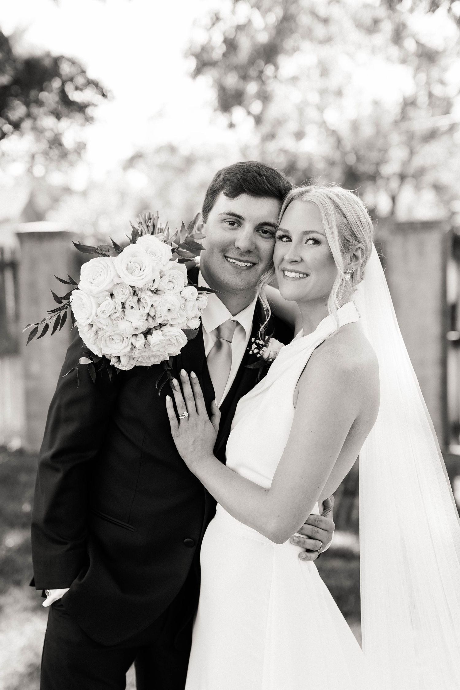 Romantic black and white wedding portrait with white bouquet and classic attire.