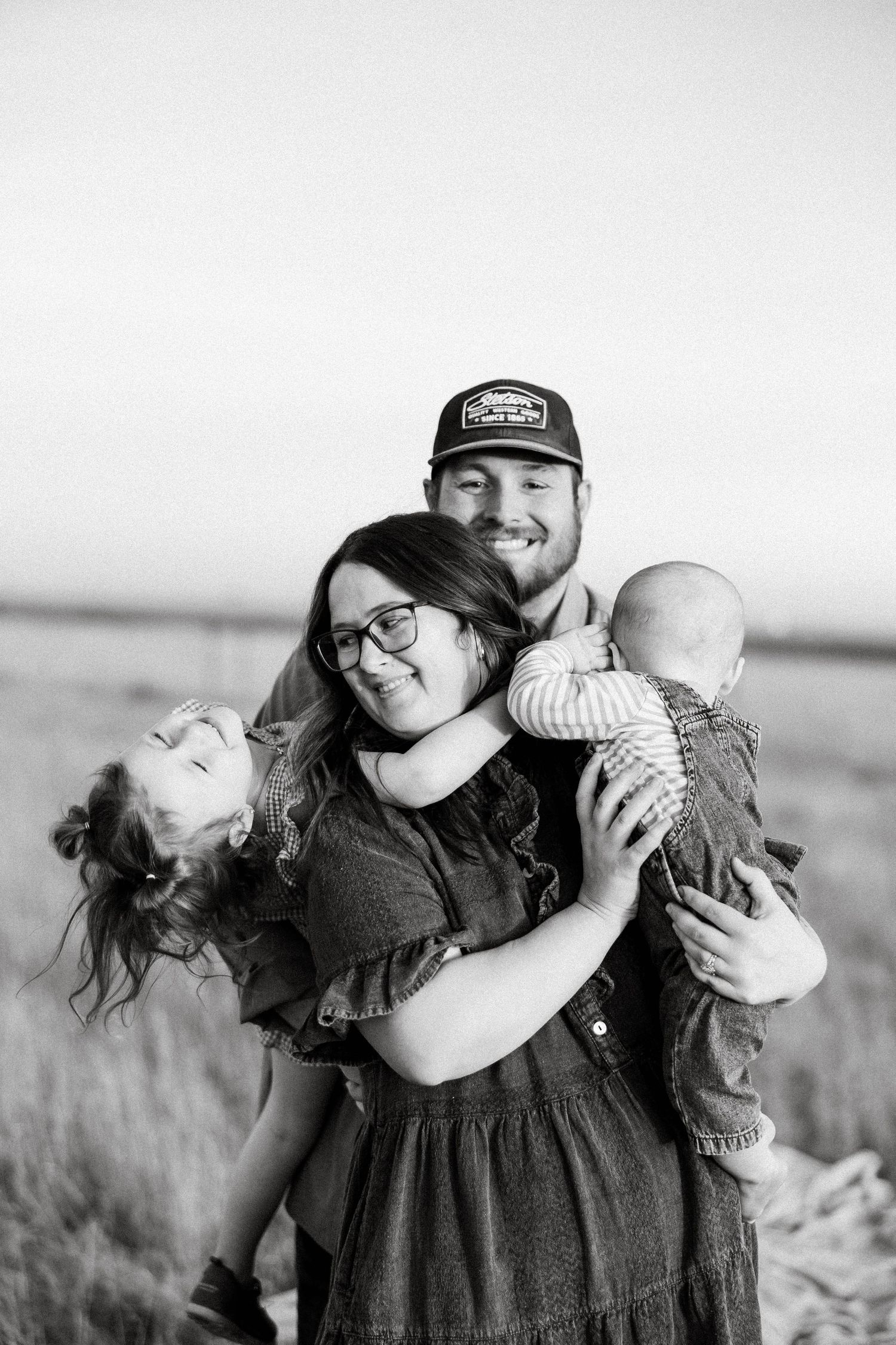 A series of black and white photos showing a couple embracing and laughing together in a field.