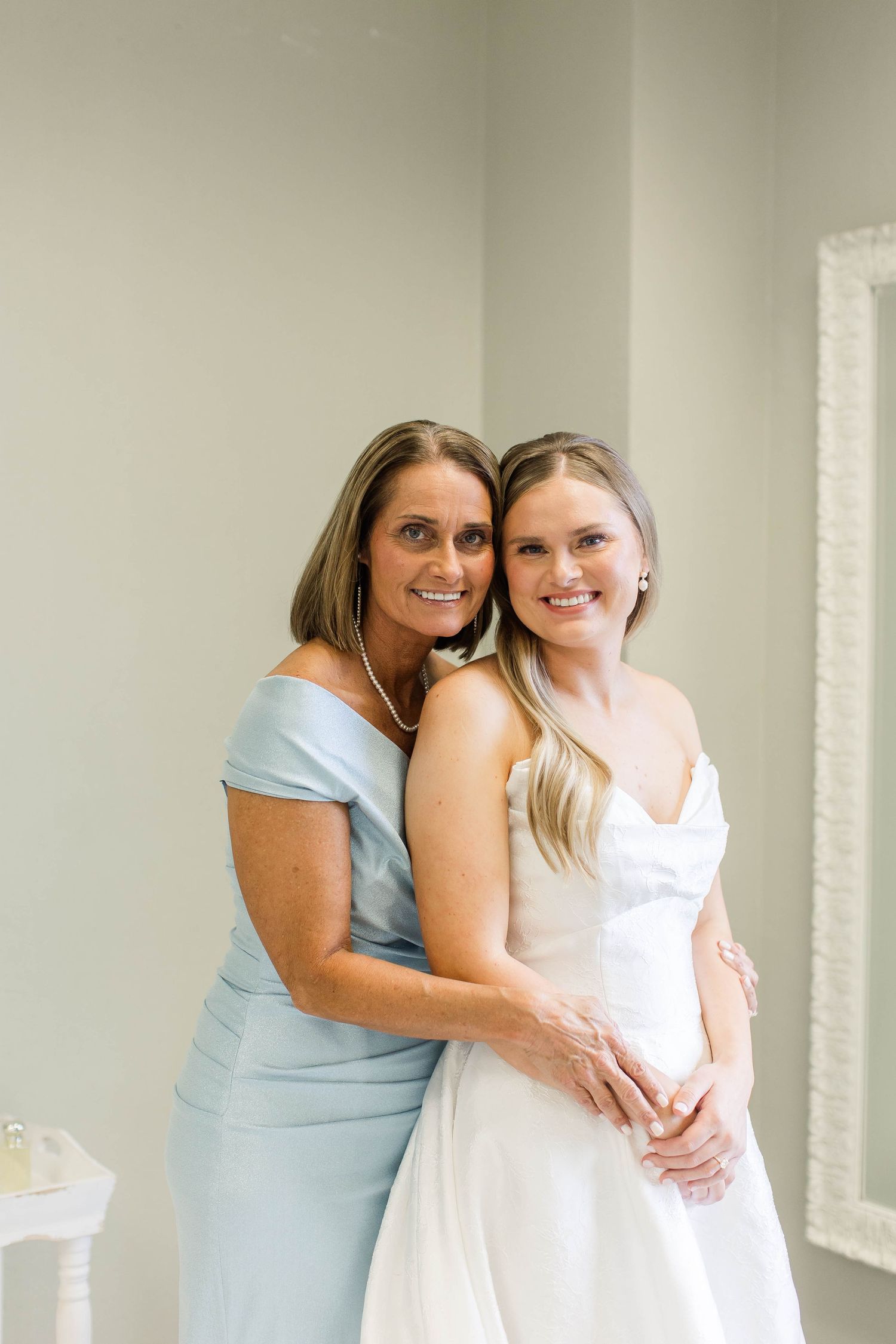 Wedding party members sharing emotional moment in light-filled room.